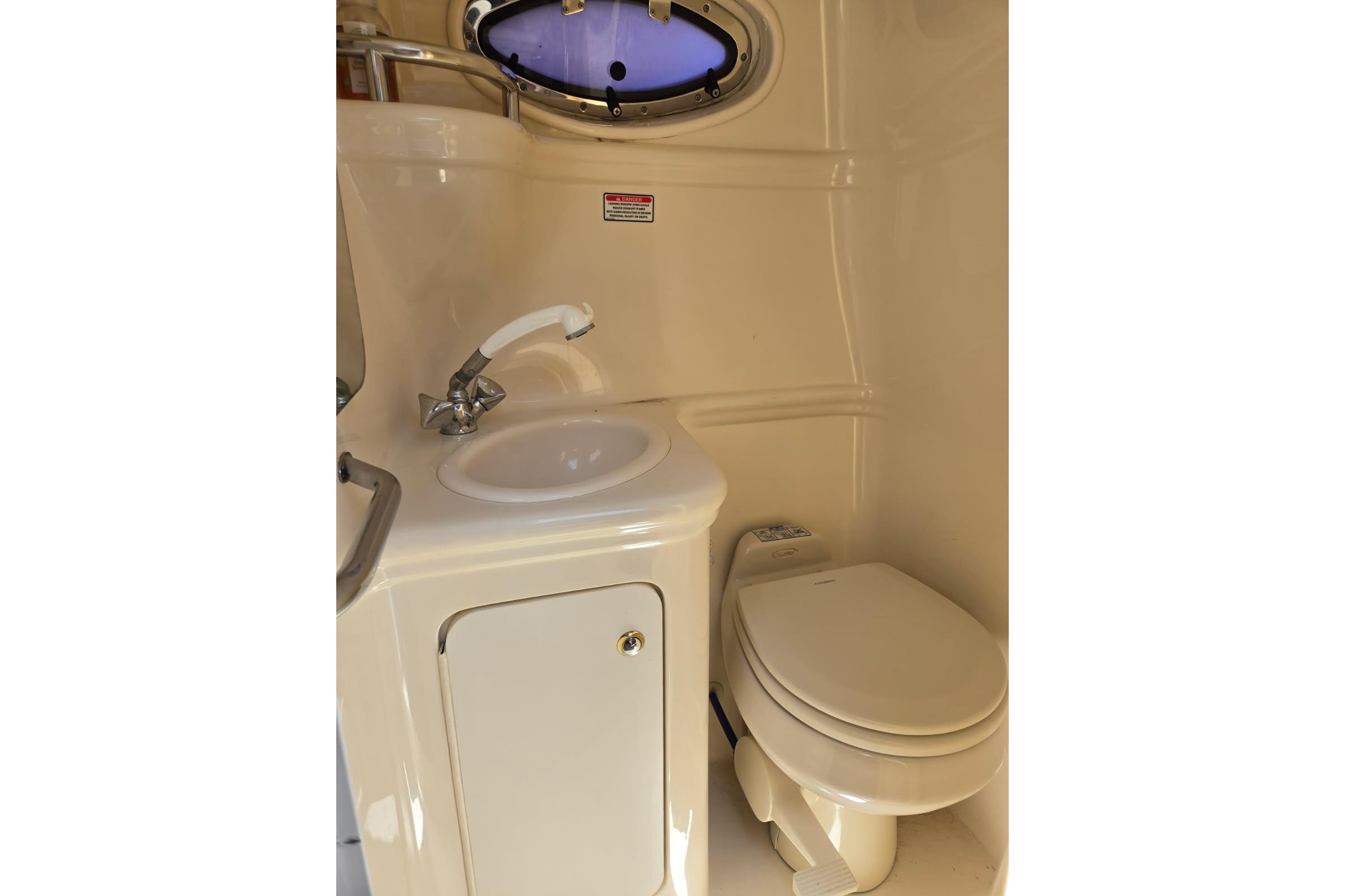 Compact bathroom in 2004 Sea Ray Sundancer 260 boat, featuring sink and toilet.