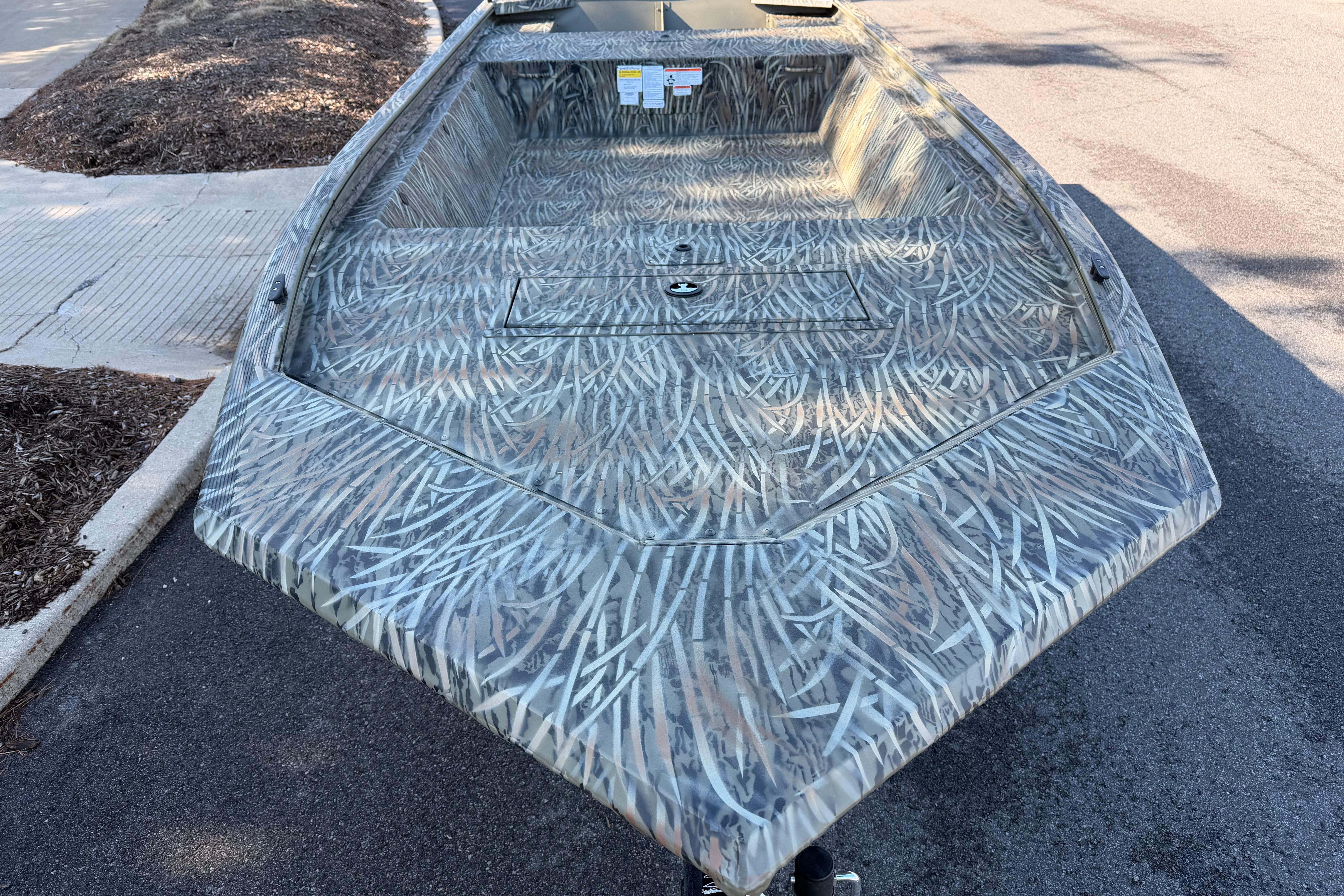 2026 Tracker Grizzly 1648 Utility boat with camouflage pattern on a street.