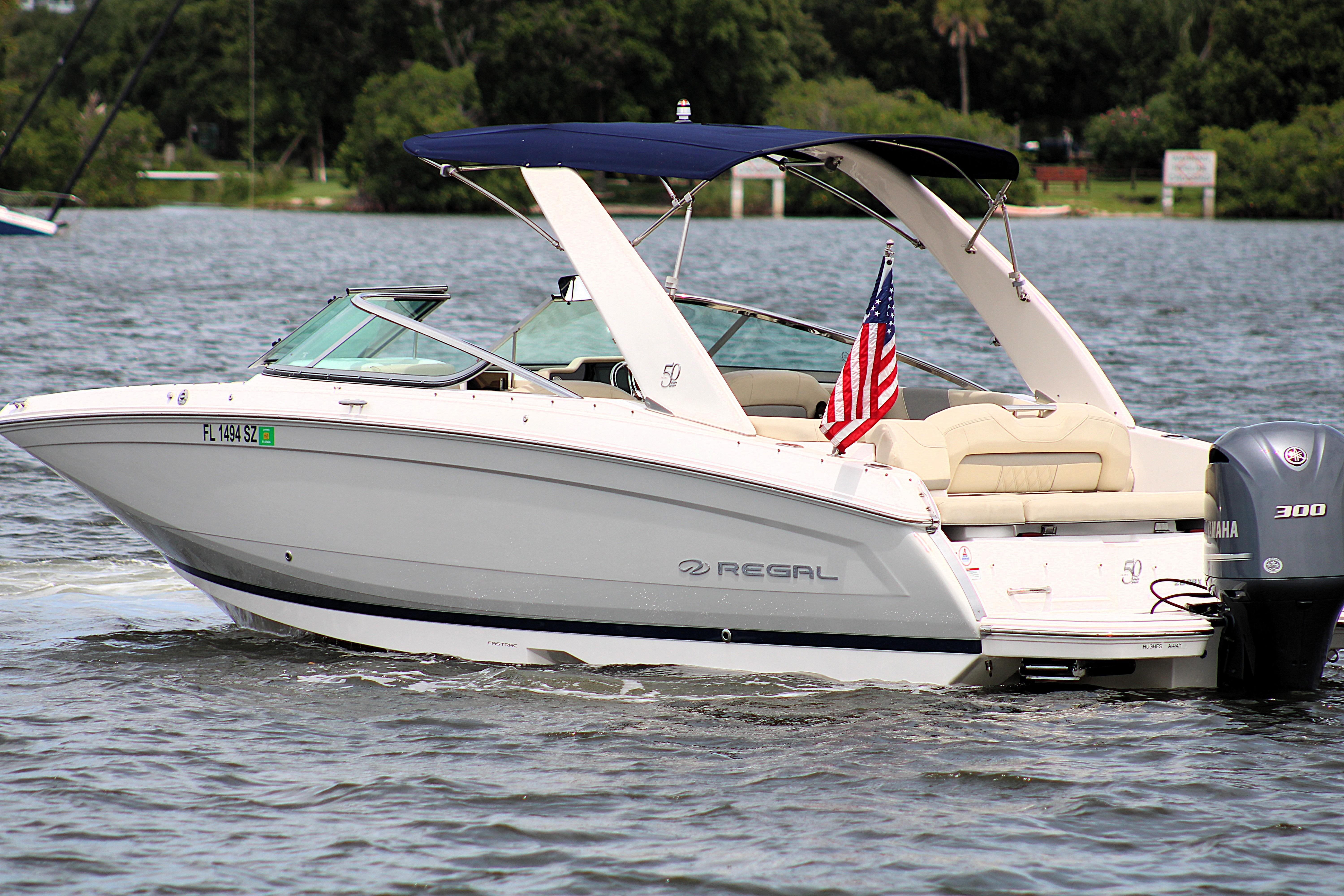 2021 Regal 26 OBX boat cruising on a lake with an American flag.