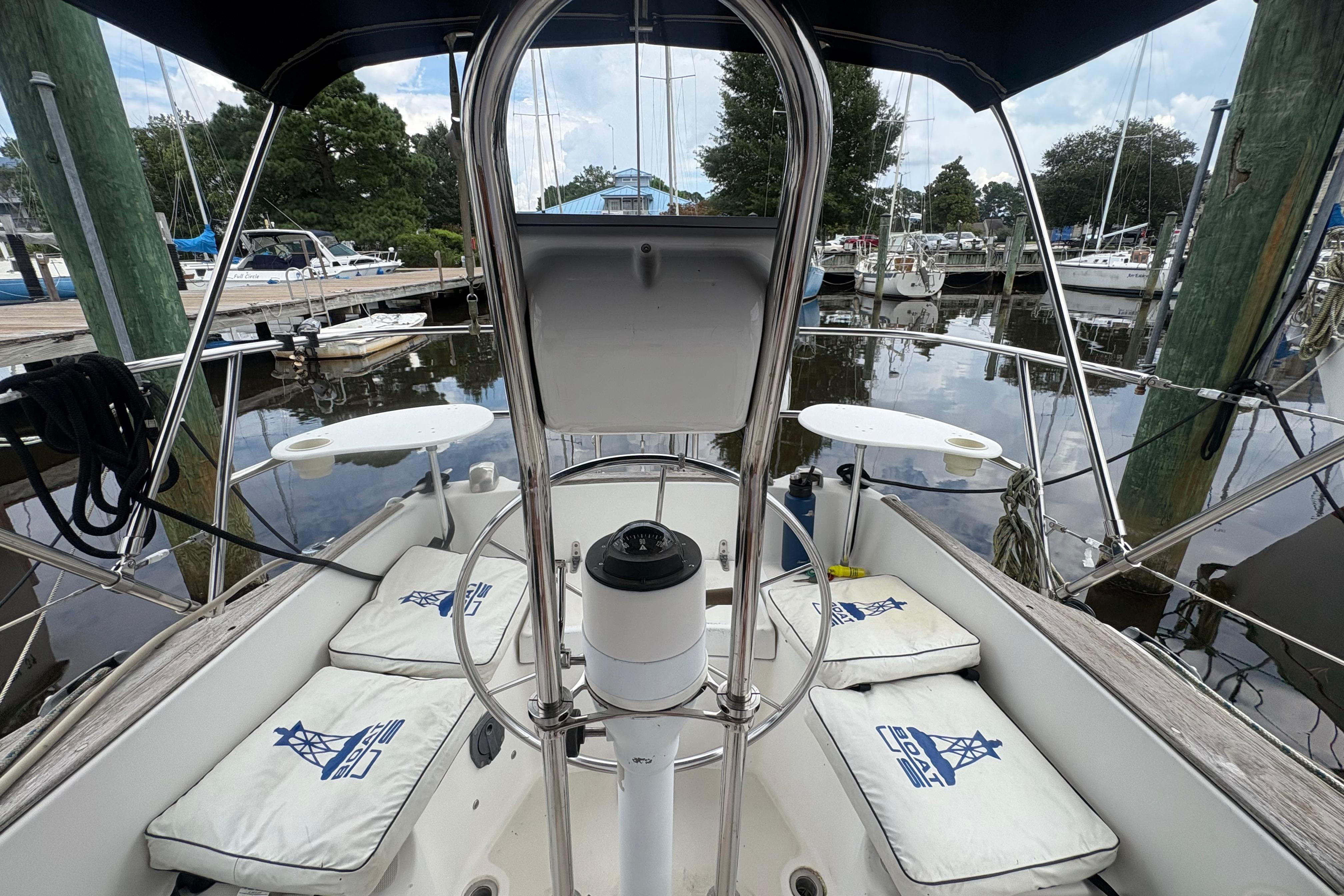 Cockpit of 1981 Sabre 31 sailboat docked at marina, featuring cushioned seating and steering wheel.
