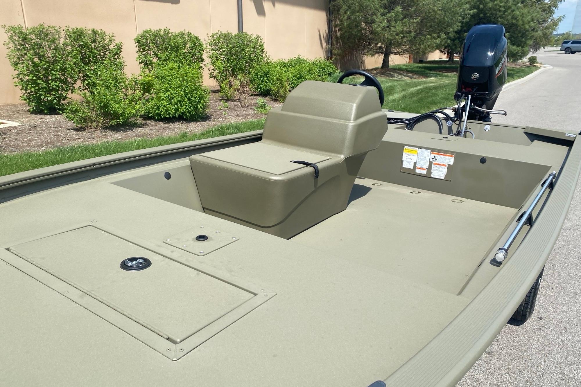 2026 Tracker Grizzly 1648 SC boat, olive green, parked outdoors, showcasing seating and motor.