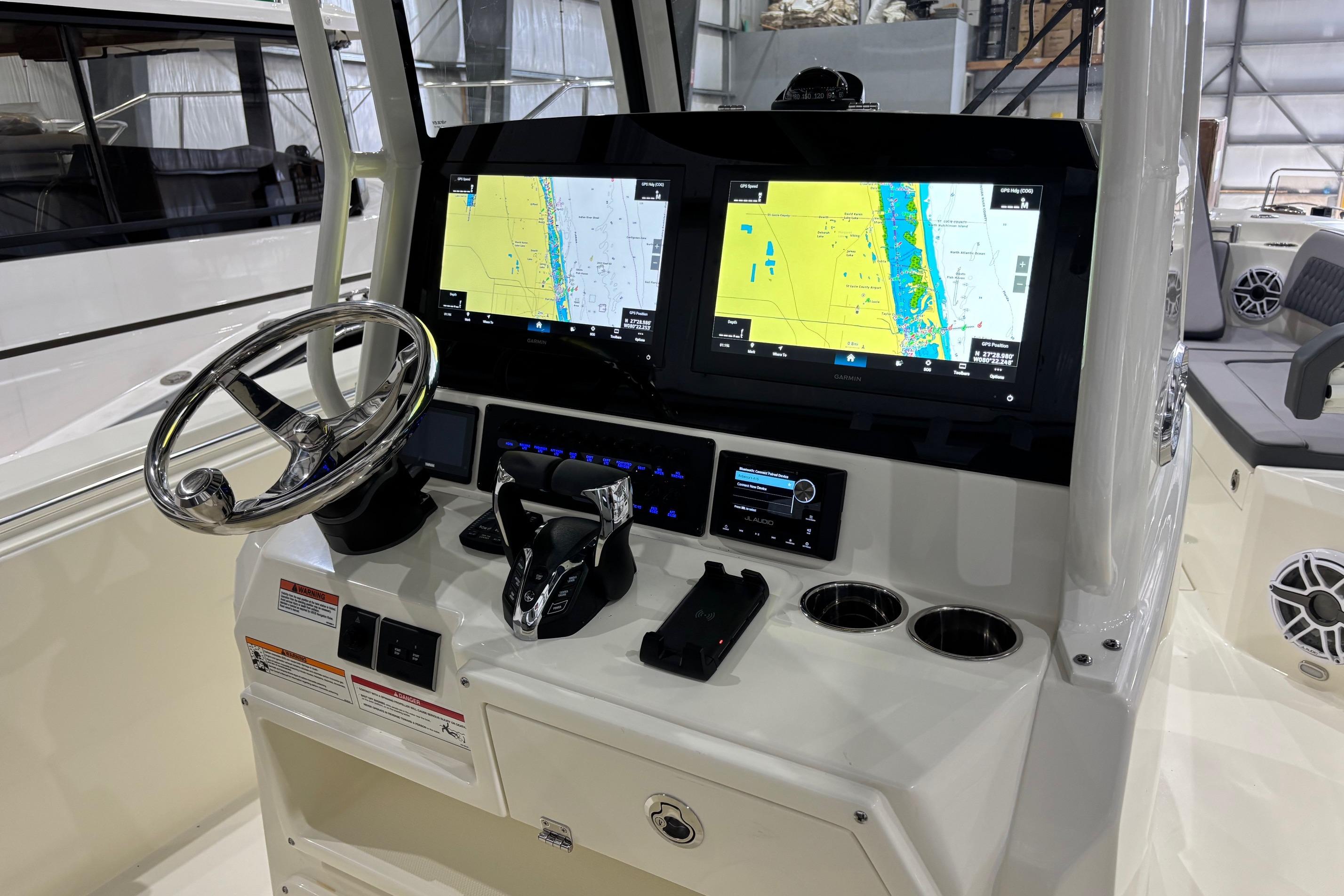 2026 Cobia 285 Open Center Console helm with dual navigation screens and steering wheel.