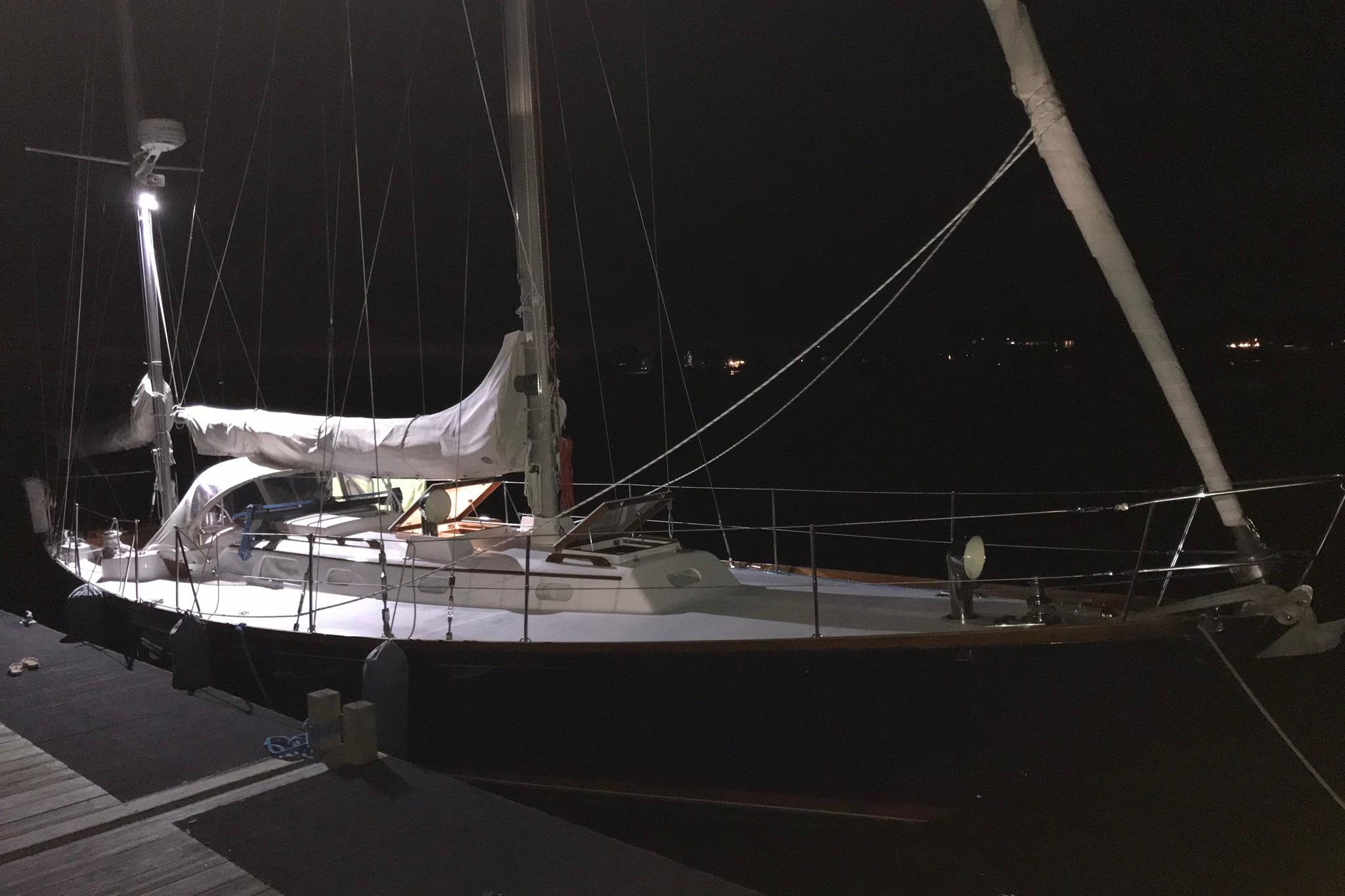 1970 Hinckley Bermuda 40 sailboat docked at night, illuminated by deck lights.