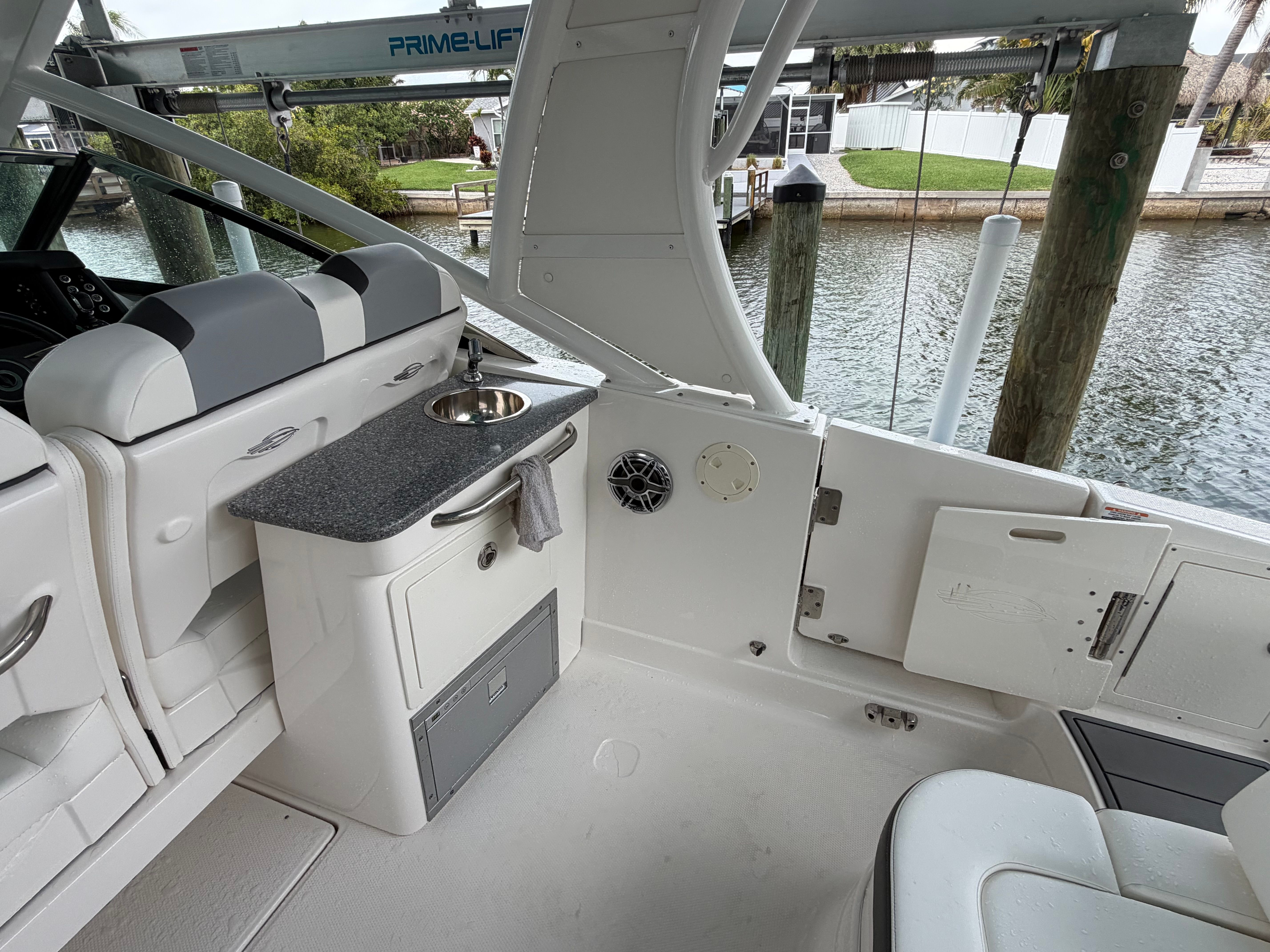 The boat features a small sink and outdoor seating, docked by the water.