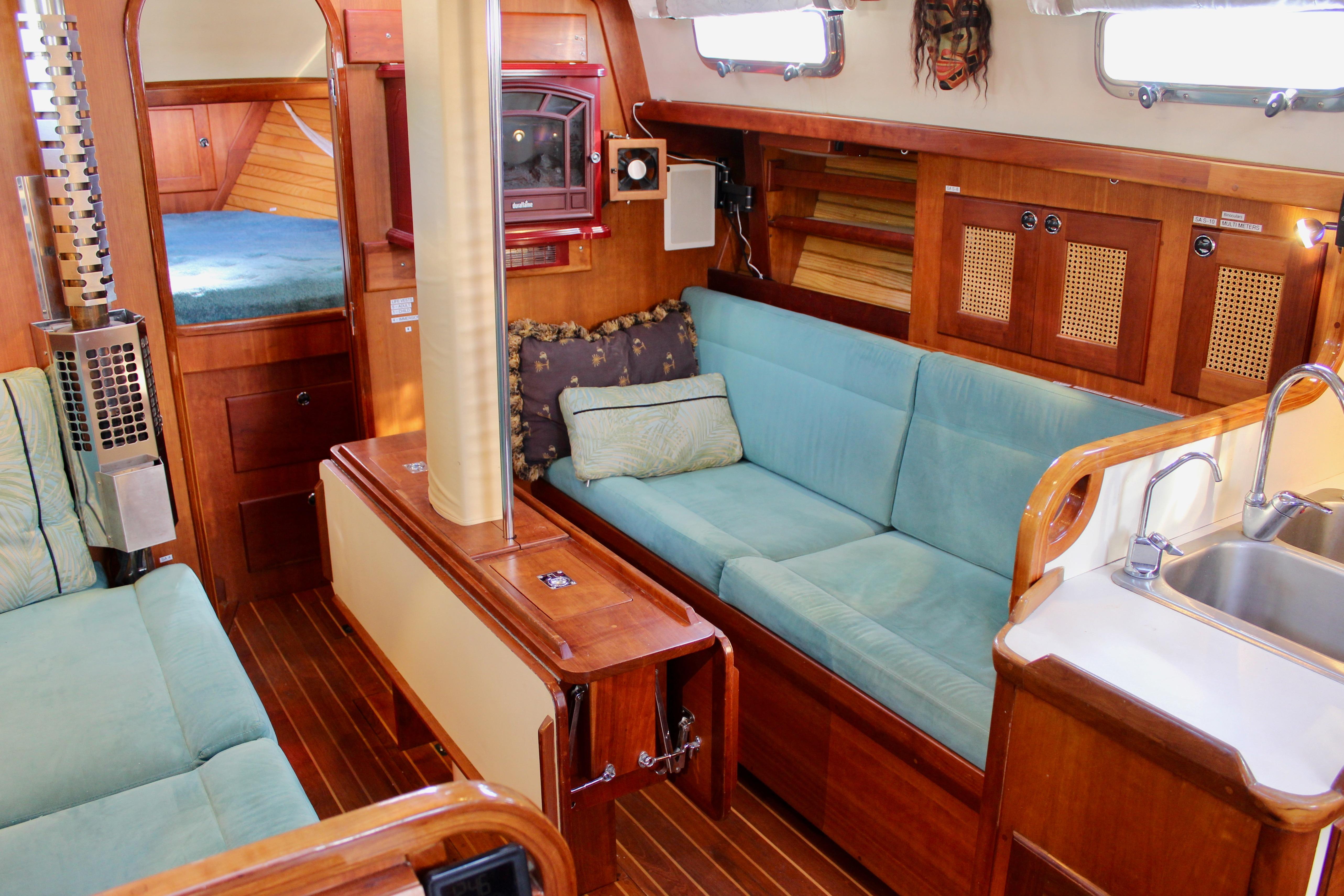 Cozy interior of 1997 Valiant 39 sailboat with wooden finishes and teal seating.