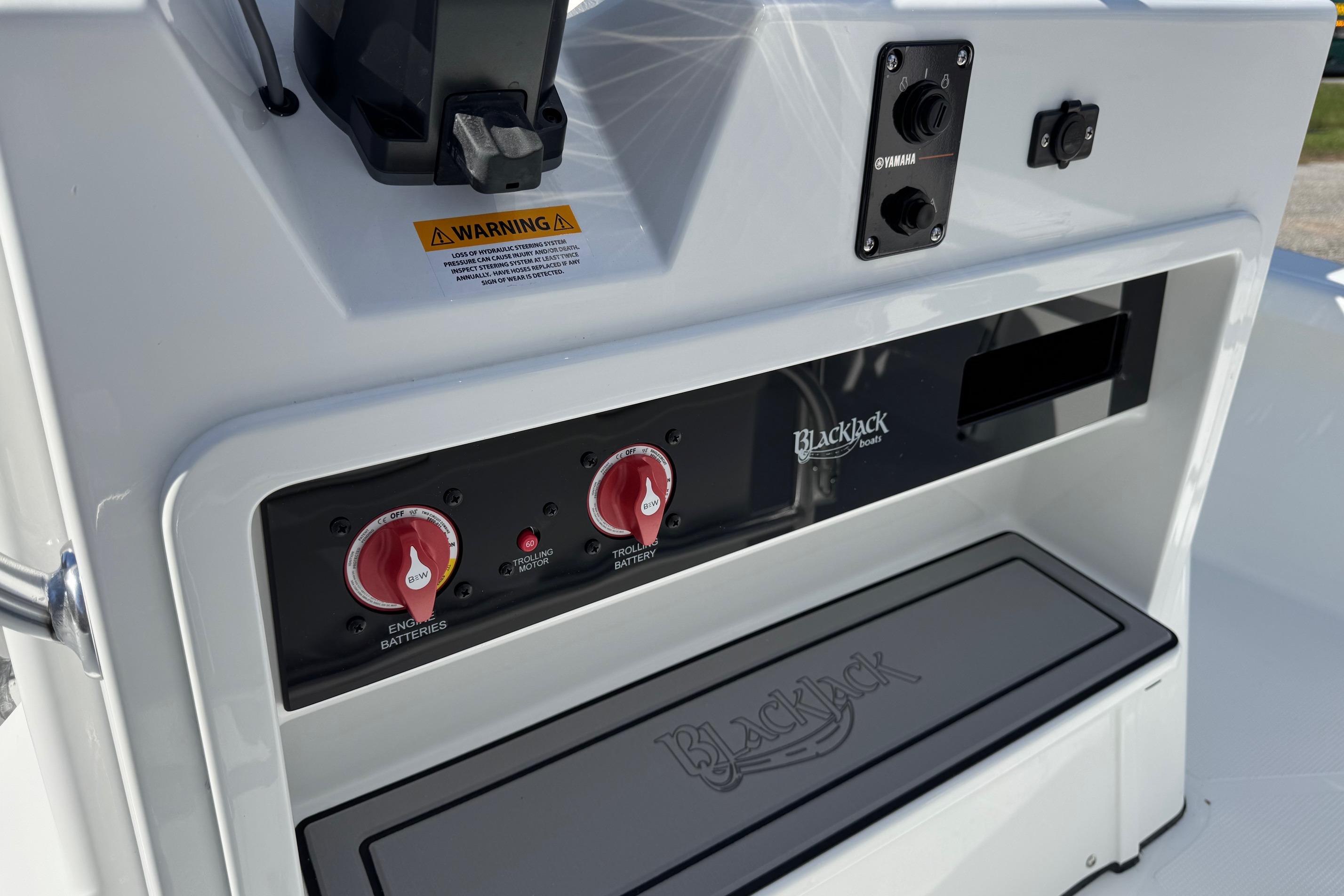 Control panel of 2026 BlackJack 256 Bay boat with battery switches and warning label.