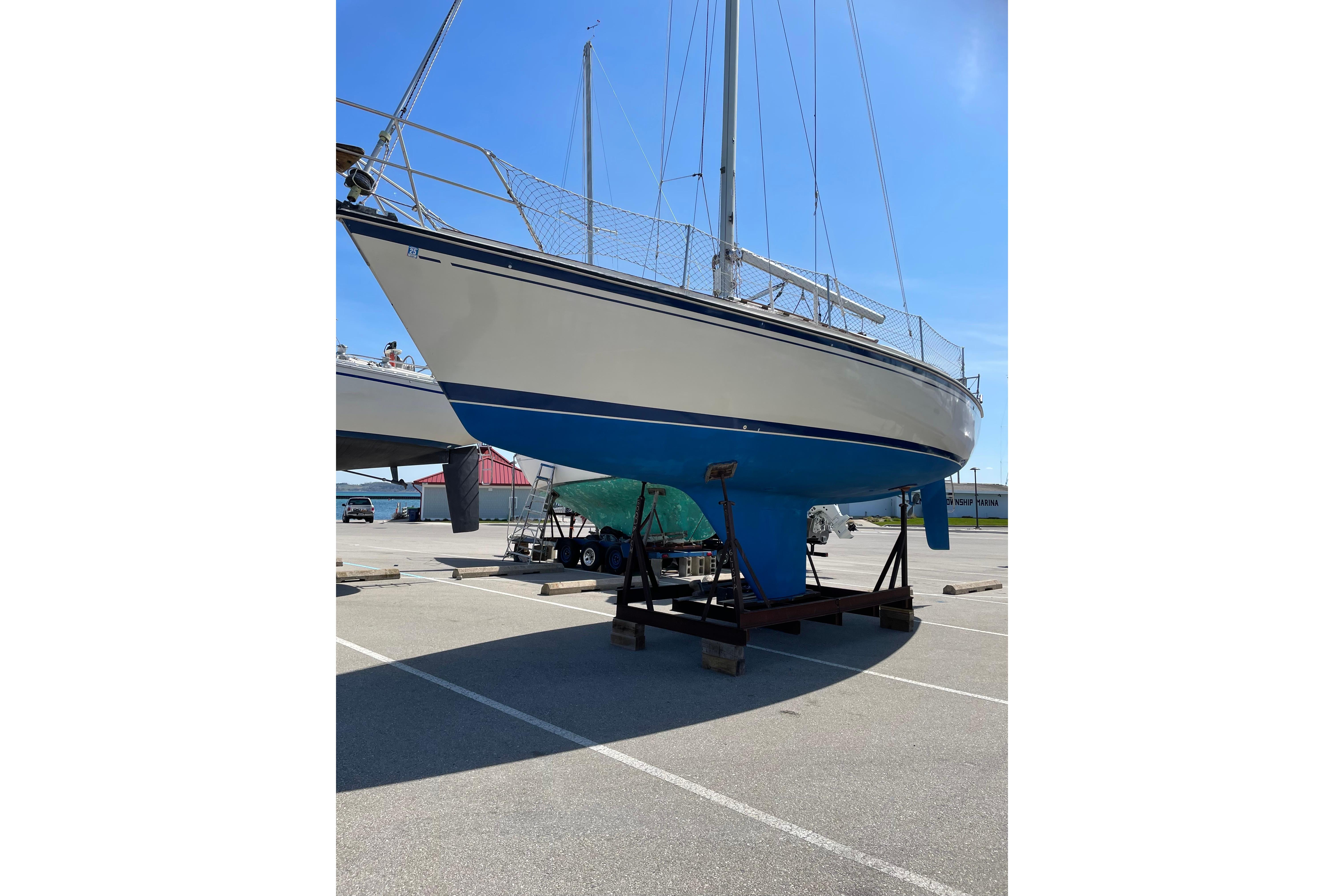 1983 O'Day 34 sailboat on dry dock, blue and white hull, sunny day.