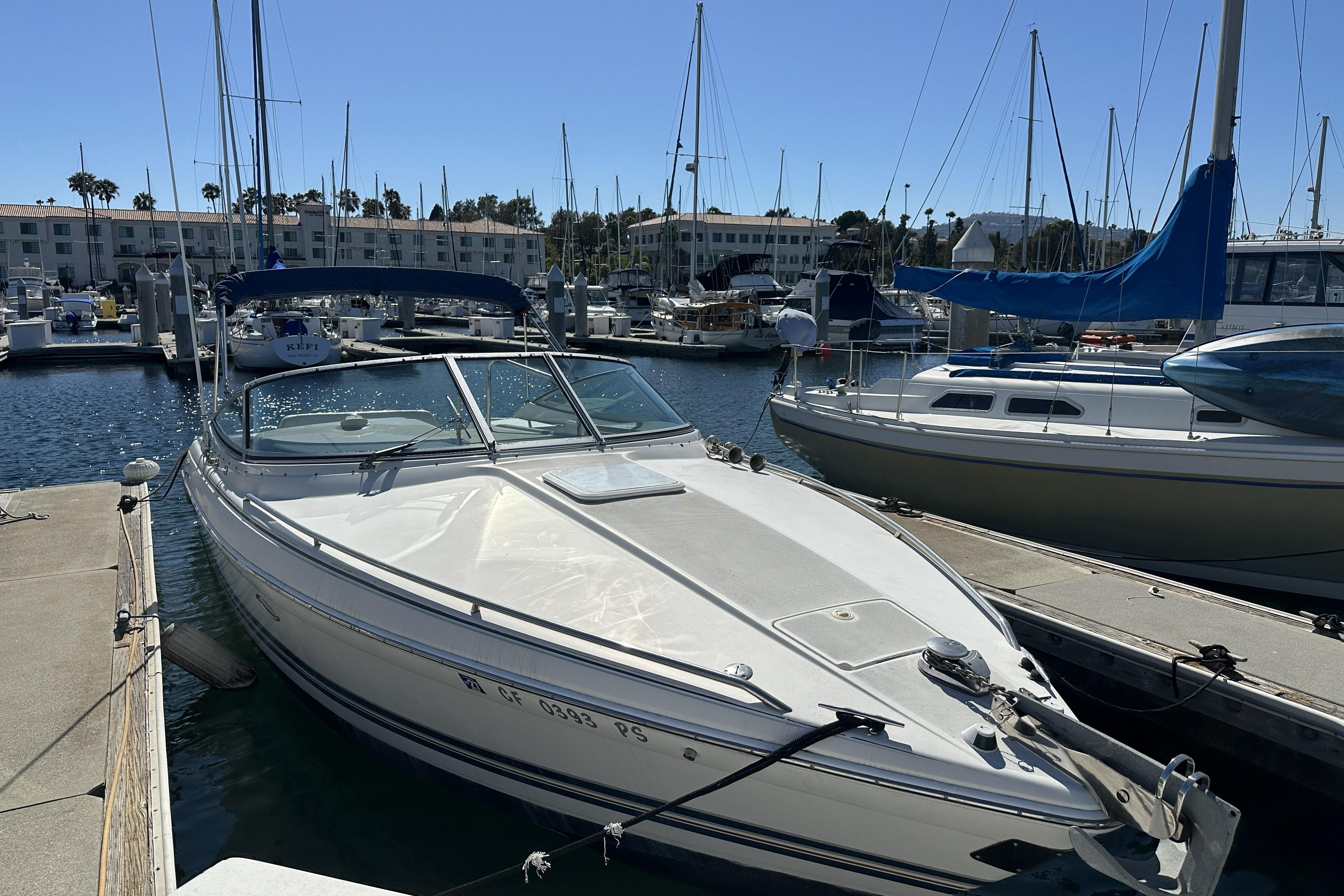 Boat docked at a marina with other sailboats in the background.