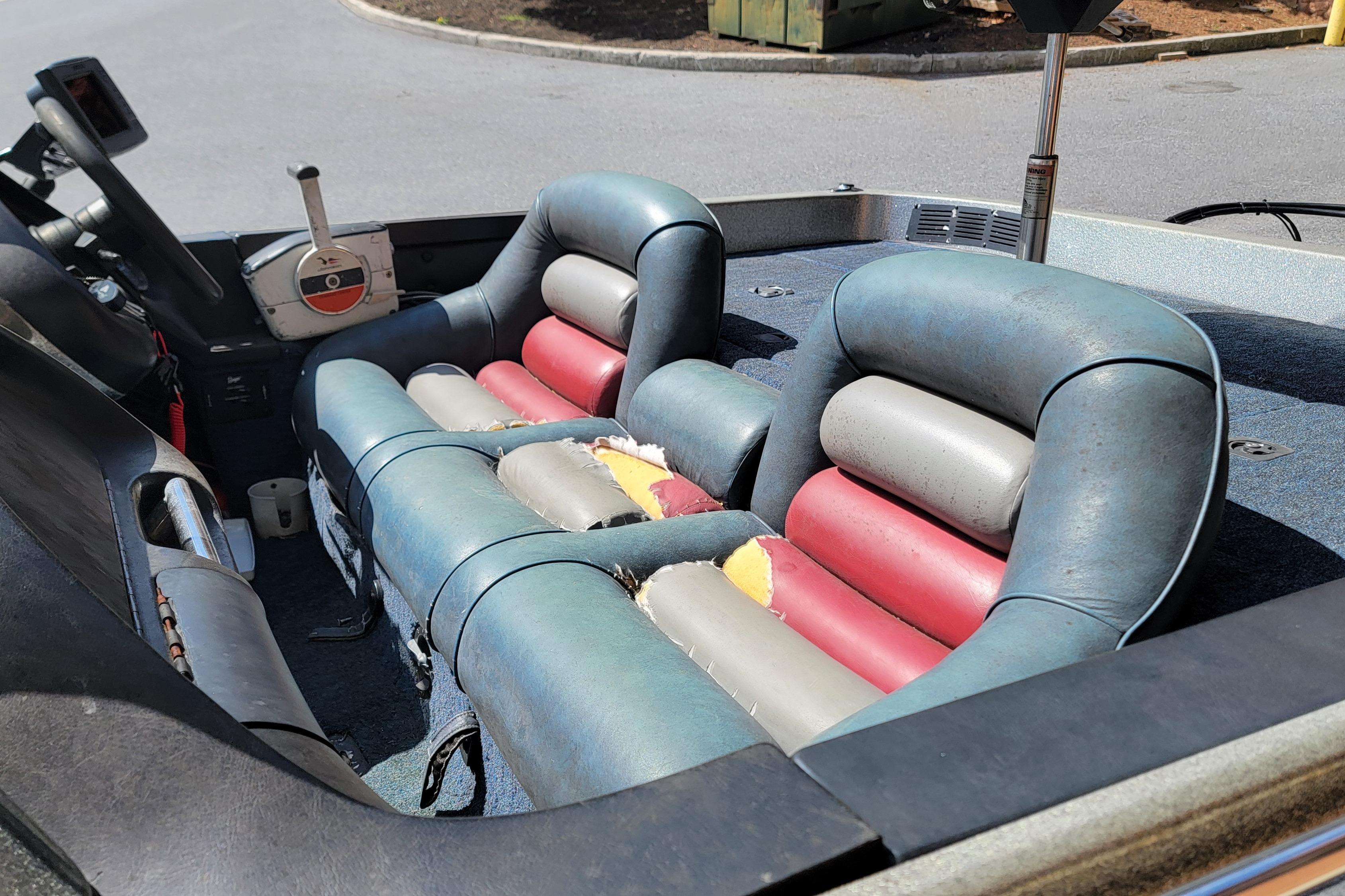 Interior of a 1995 Ranger boat with worn, colorful seats and steering controls.