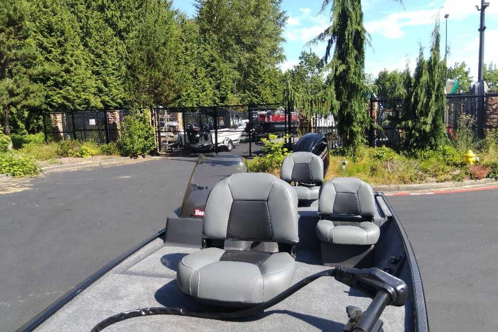 2026 Tracker Bass Tracker Classic XL boat with gray seating, parked outdoors near trees.