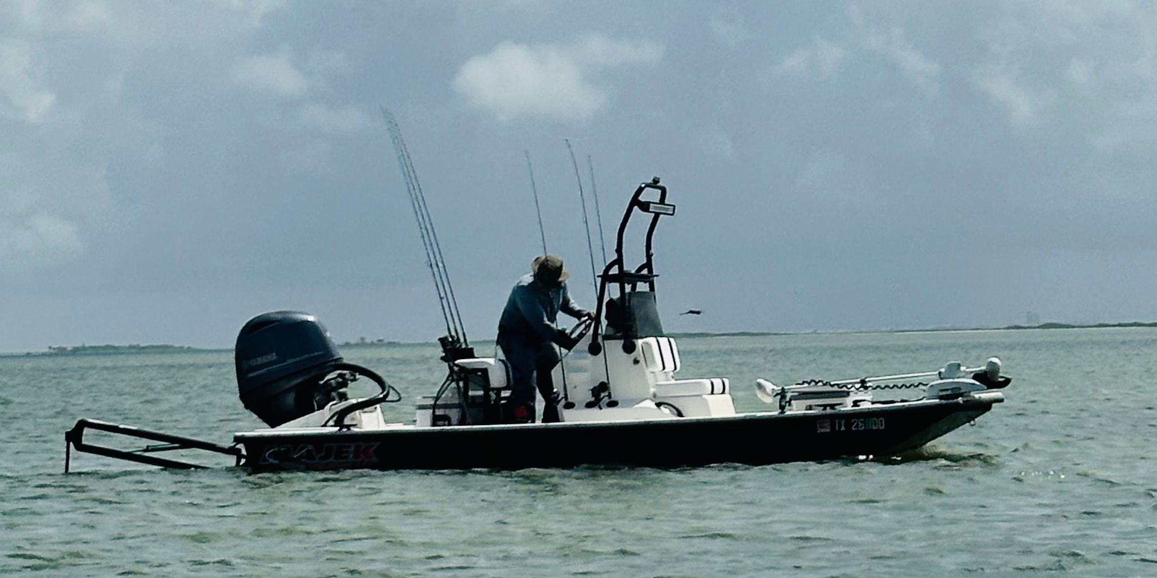 An angler stands on a 2015 Majek Redfish Line boat on the water.