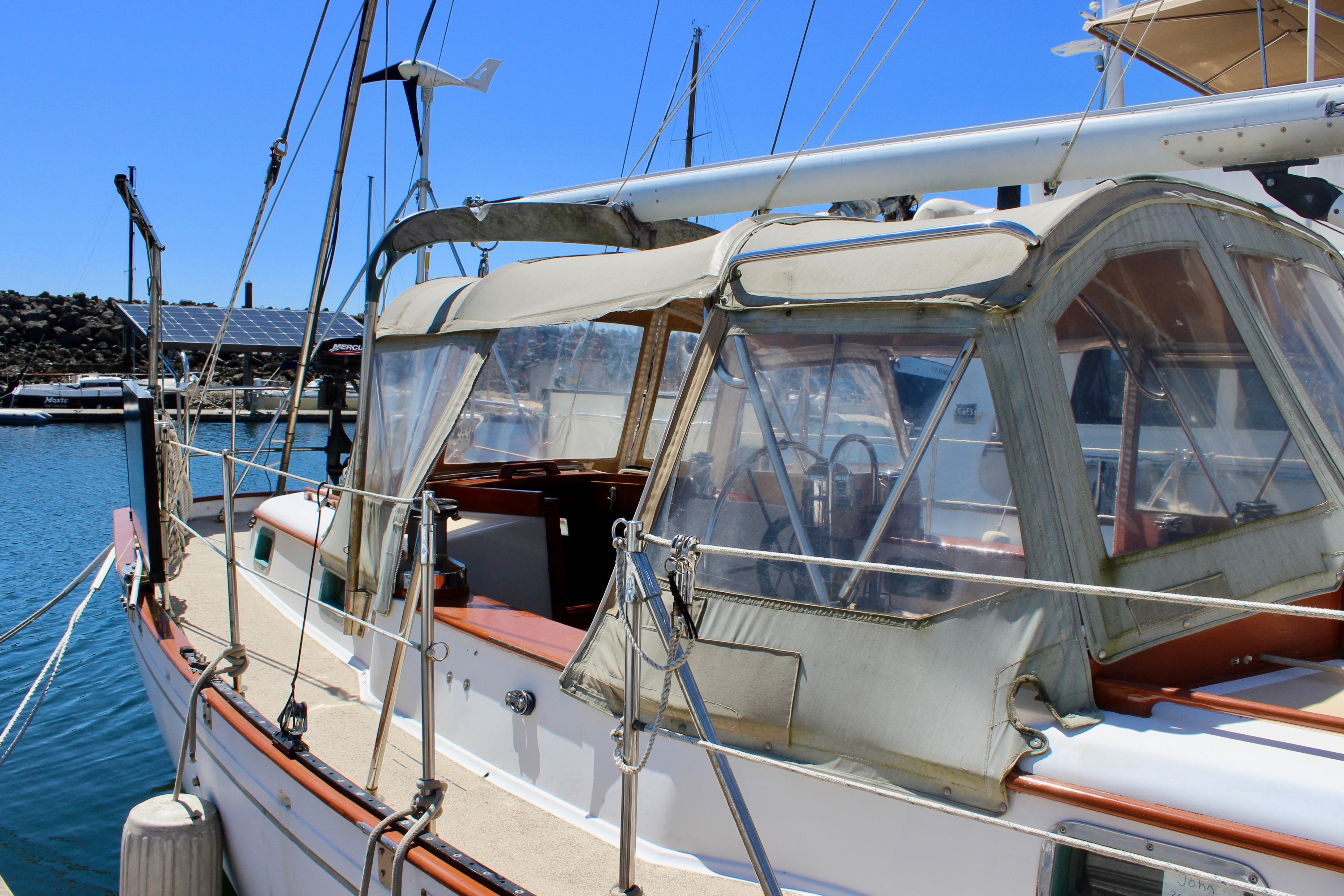 1981 Kelly Peterson 46 sailboat docked in marina, featuring a covered cockpit and clear skies.