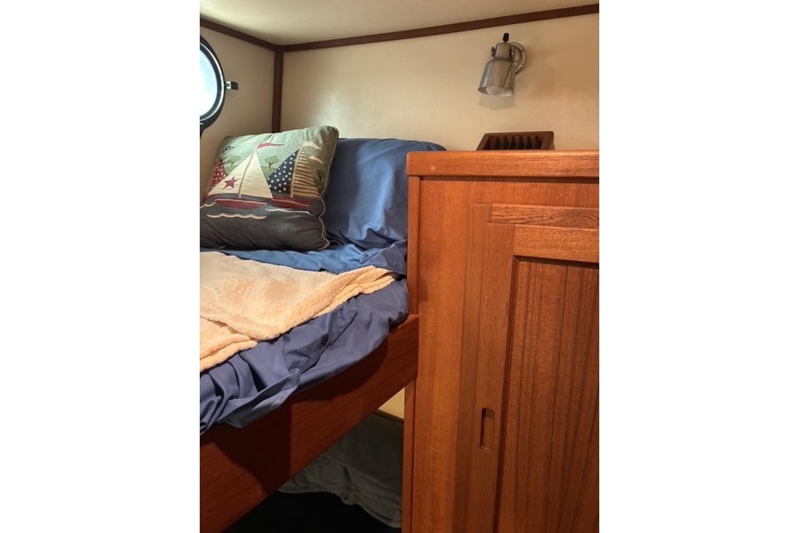 Cozy cabin interior of 2000 Nordic Tug 37 with nautical-themed pillow and wooden cabinetry.