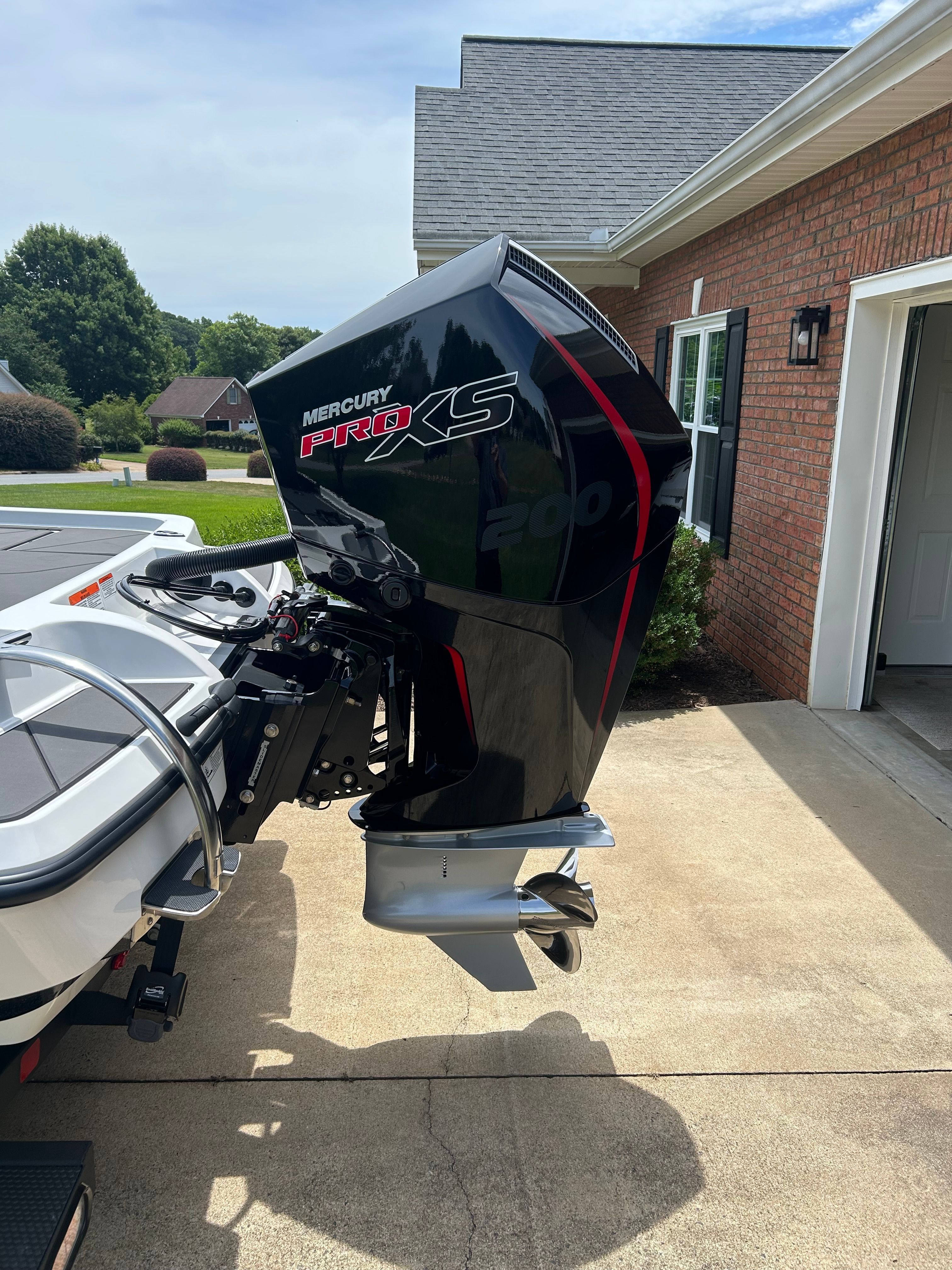 A Mercury Pro XS outboard motor is attached to a boat parked in a driveway.