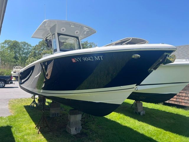 2023 Pursuit S268 parked on grass, featuring a blue hull and white top.