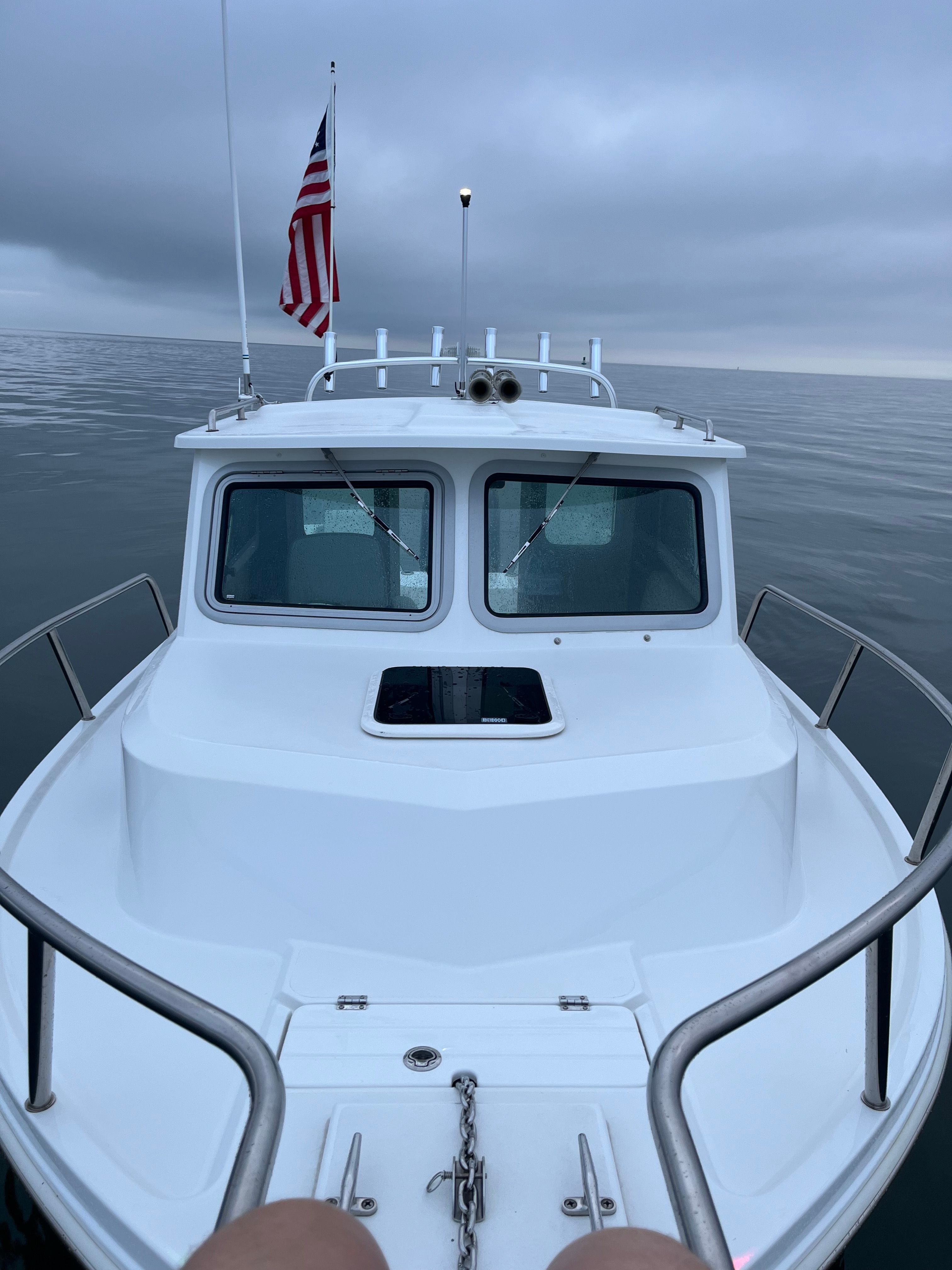 Parker 2021 sport cabin on calm water with American flag, gray sky in the background.