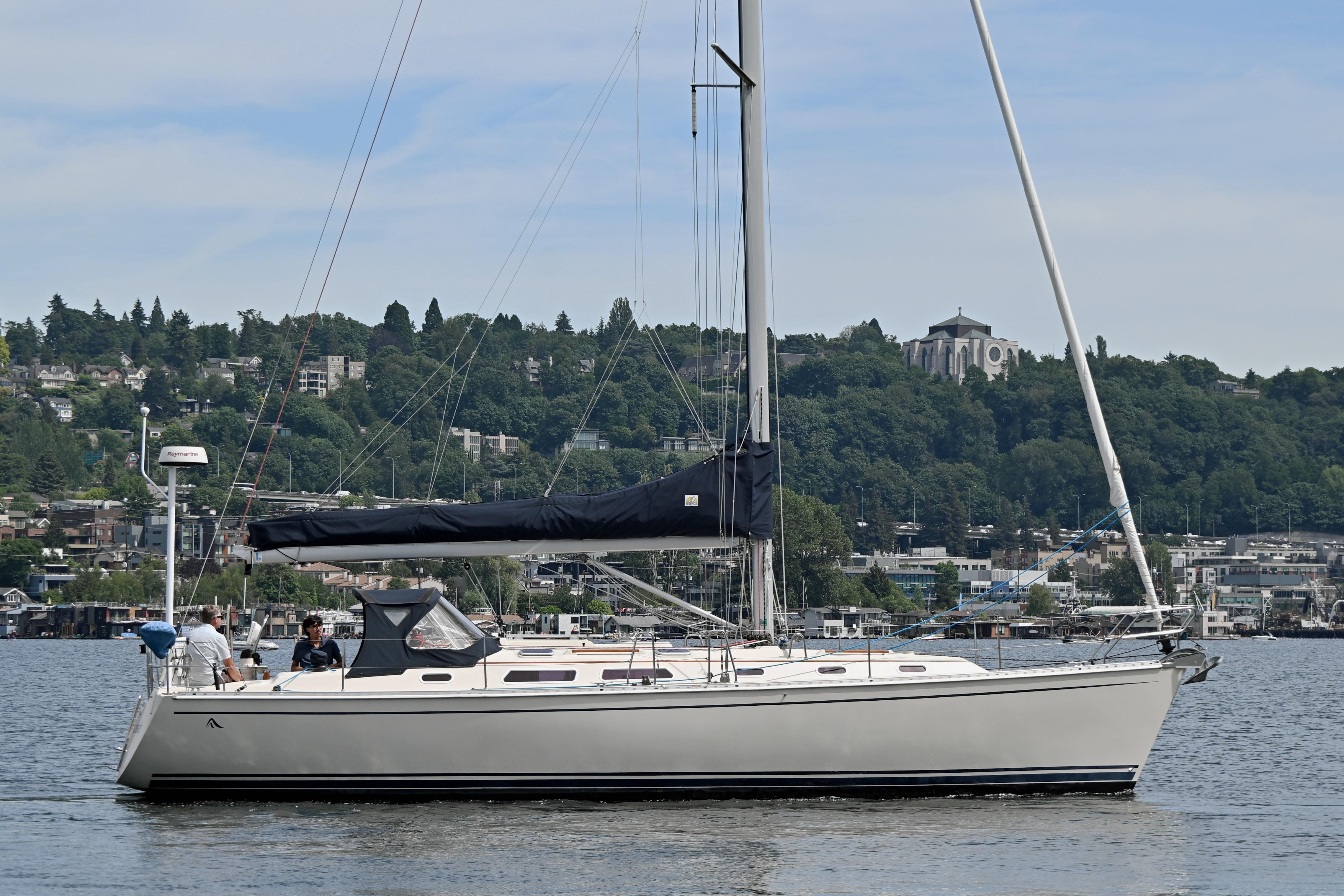 2004 Hanse 411 sailboat on a calm lake with a scenic hillside backdrop.