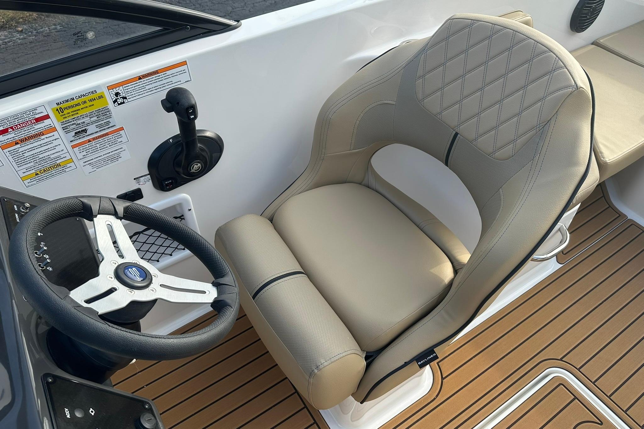 2026 Bayliner VR6 Bowrider OB cockpit with steering wheel and beige captain's chair.