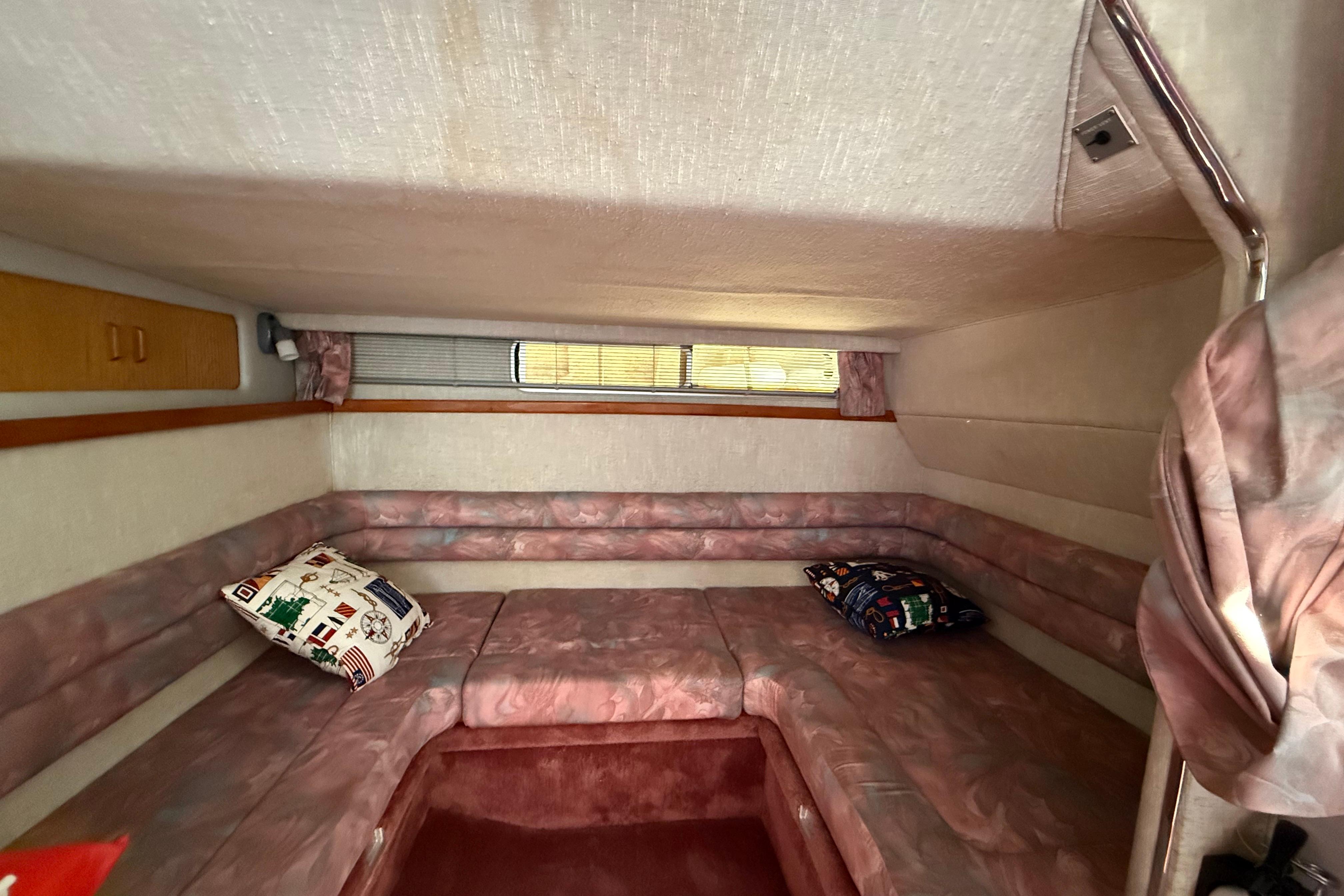 Interior cabin of a 1990 Sea Ray 310 Express Cruiser with cushioned seating and pillows.