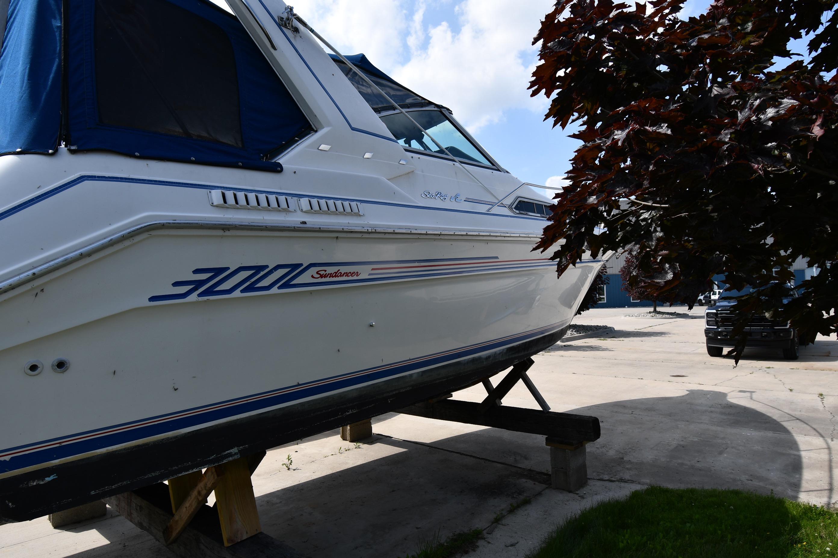 1993 Sea Ray 300 Sundancer boat on dry dock, partially shaded by tree.