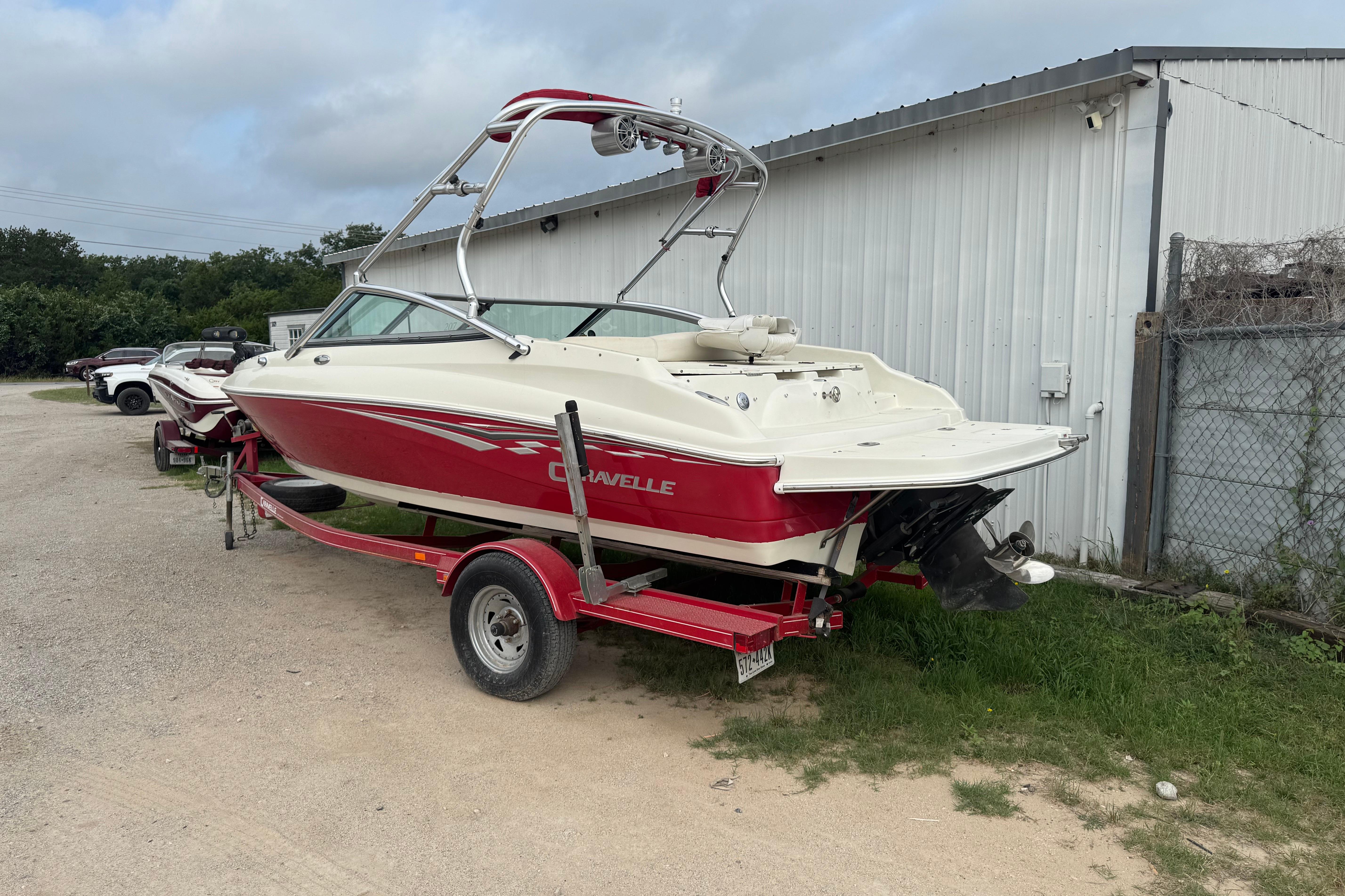 2006 Caravelle 207LS Bow Rider boat on trailer, parked outdoors near a metal building.