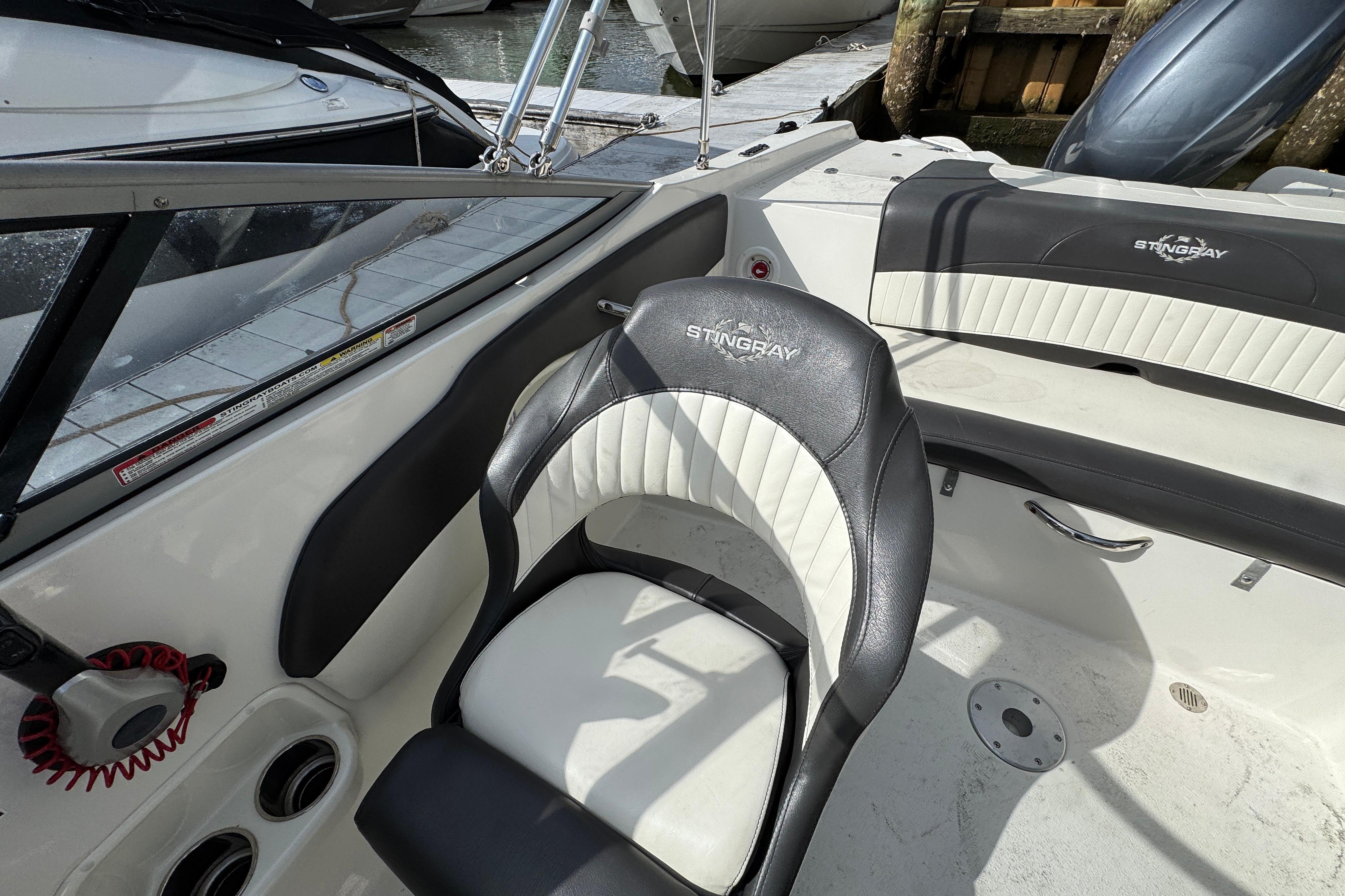 2019 Stingray 204 LR boat interior with black and white seating, docked by the water.
