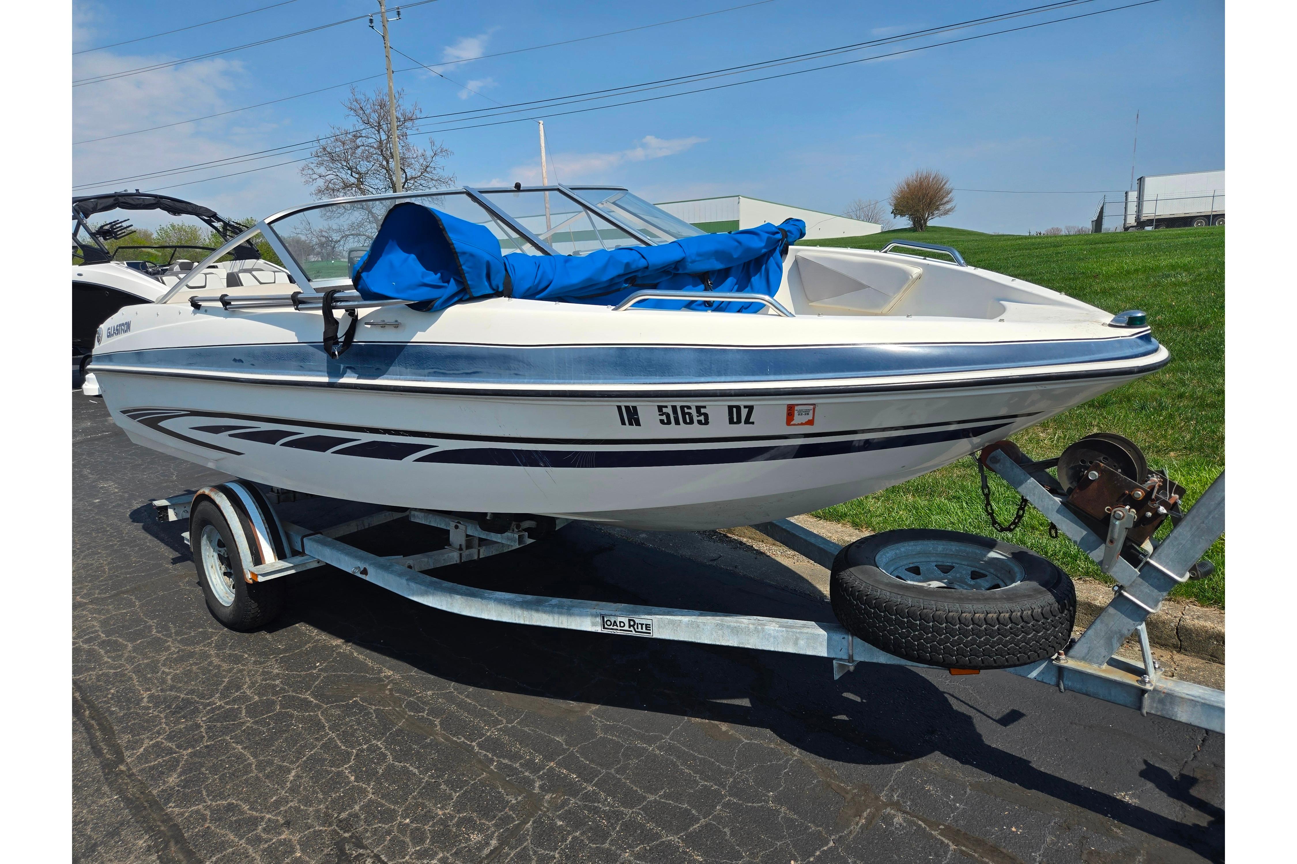 2007 Glastron GT 185 boat on trailer, parked outdoors, with blue cover.