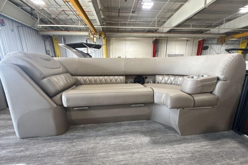 2026 Bennington 24 LXS Quadbench interior with luxurious beige seating in a spacious showroom.