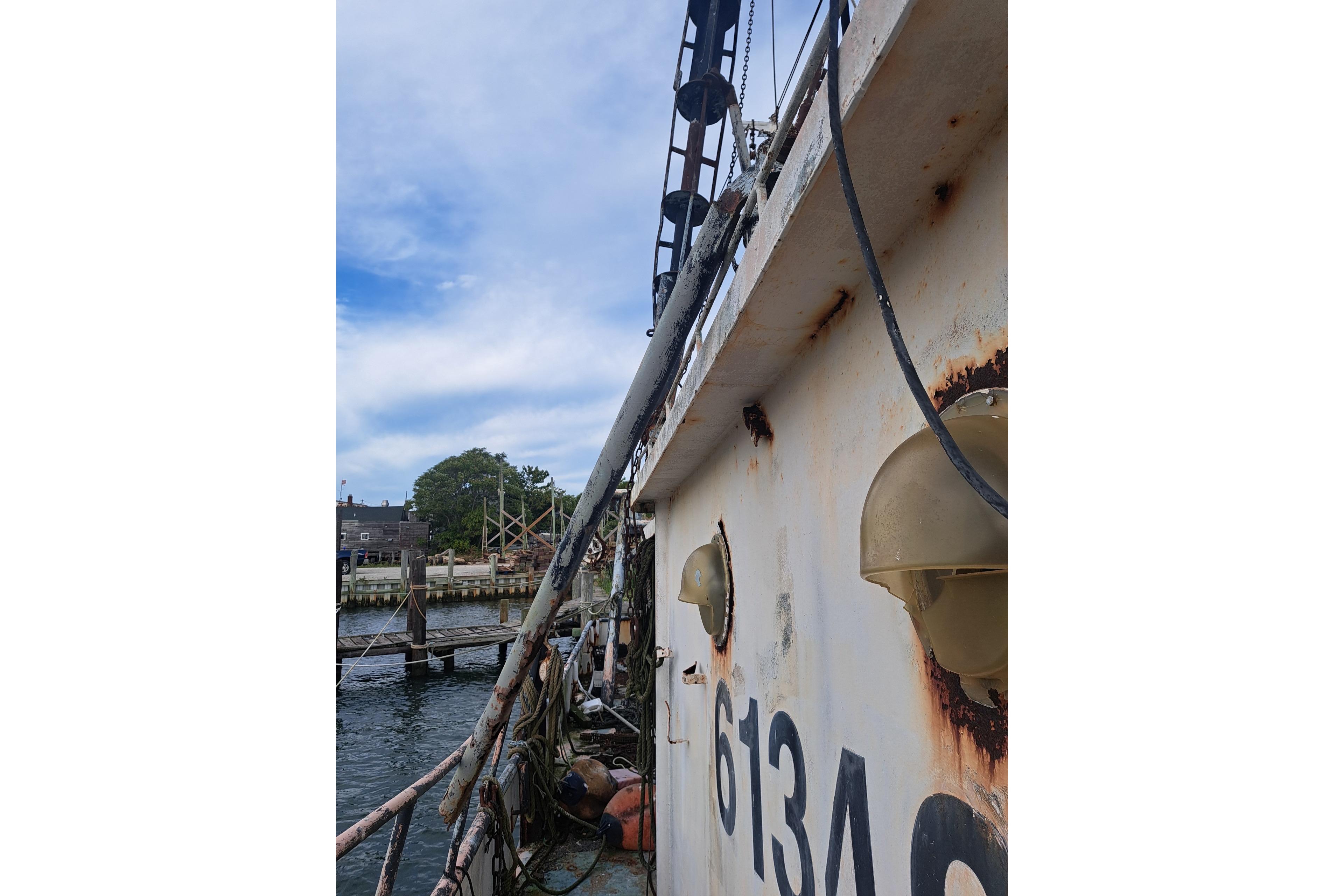 Rusty 1979 Custom Steel Trawler Dragger docked by the waterfront.