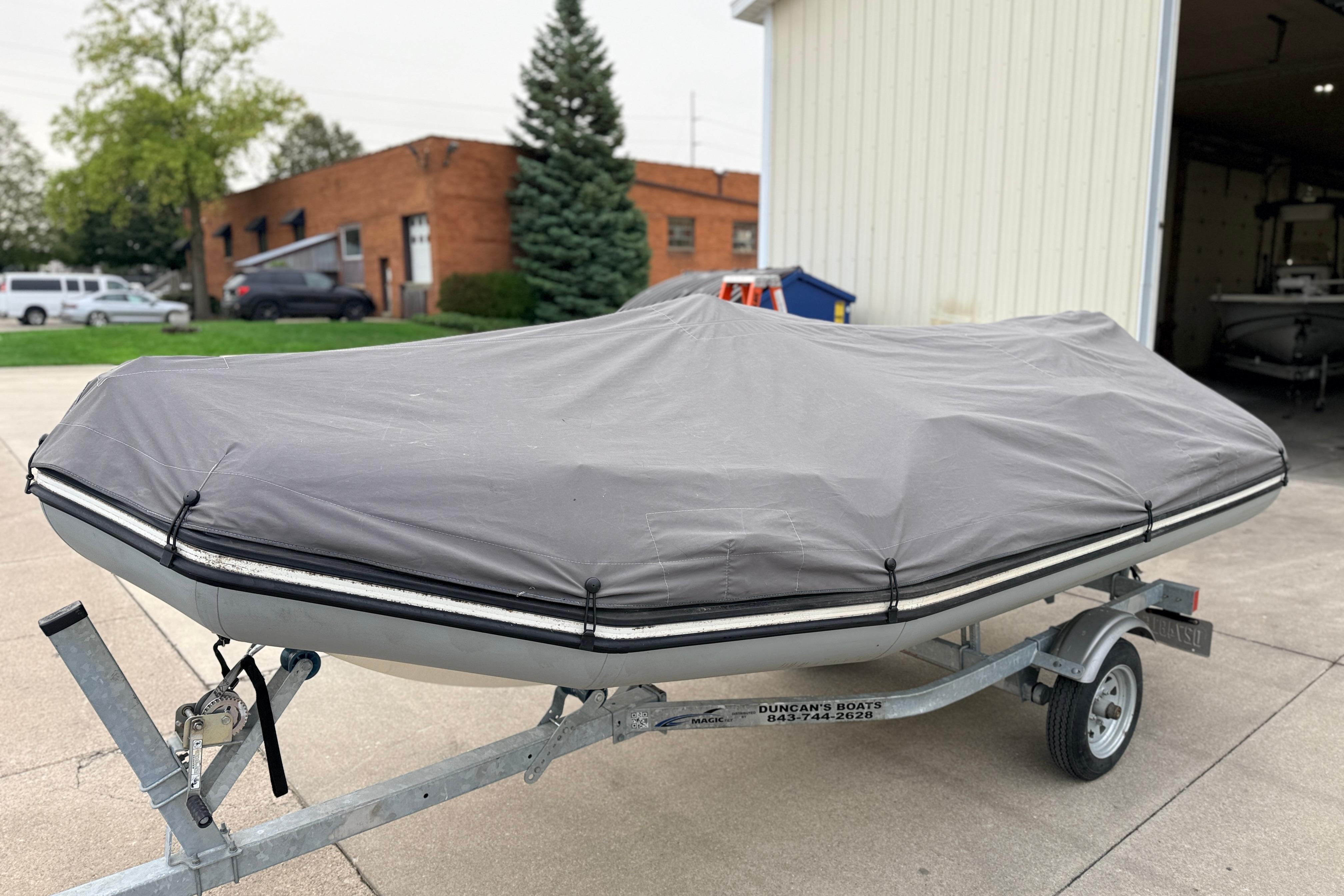 Covered 2014 Zodiac Pro Classic 420 boat on trailer outside a garage.