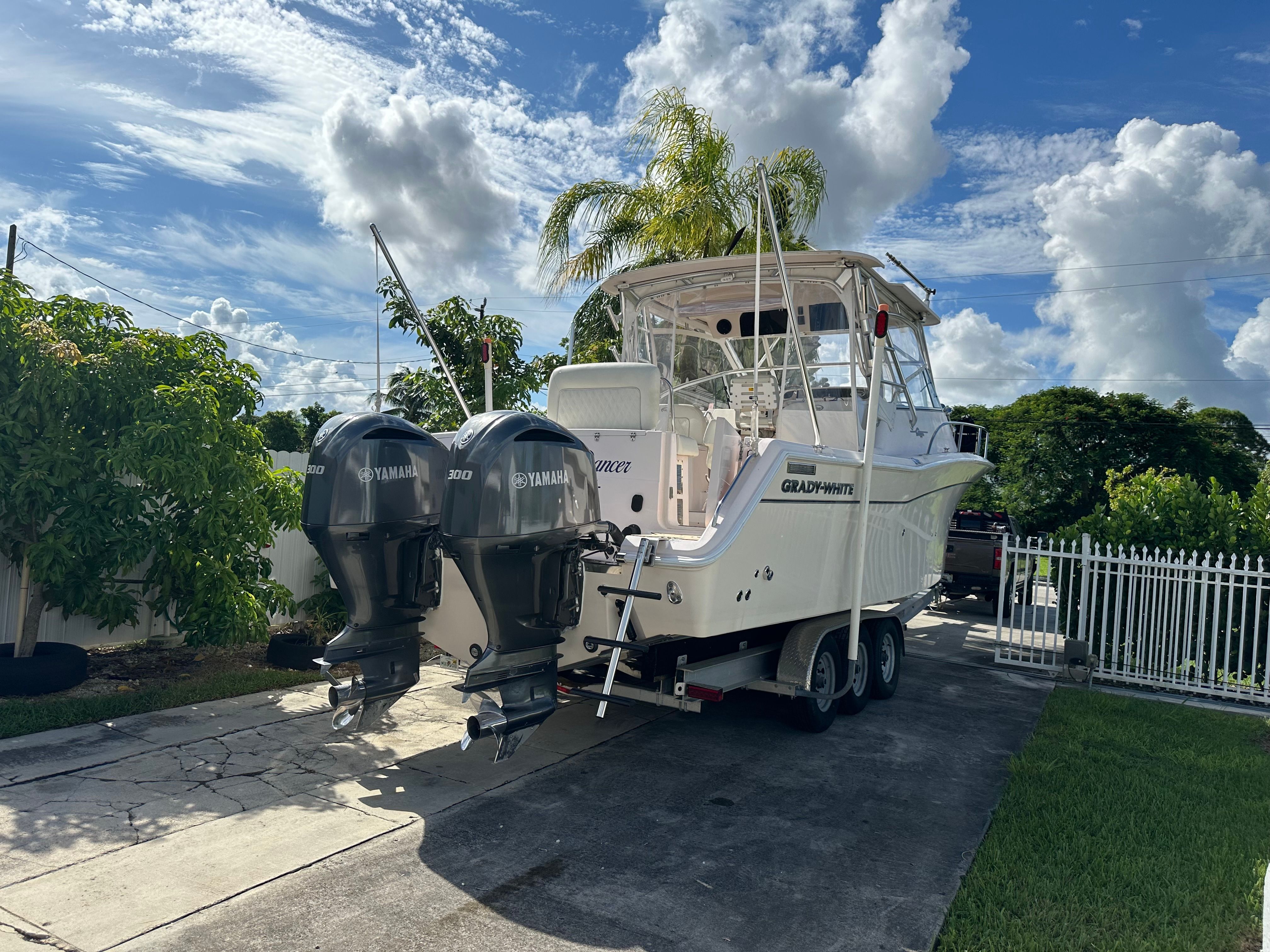 A 2003 Grady-White Express 330 boat on a trailer in a driveway.