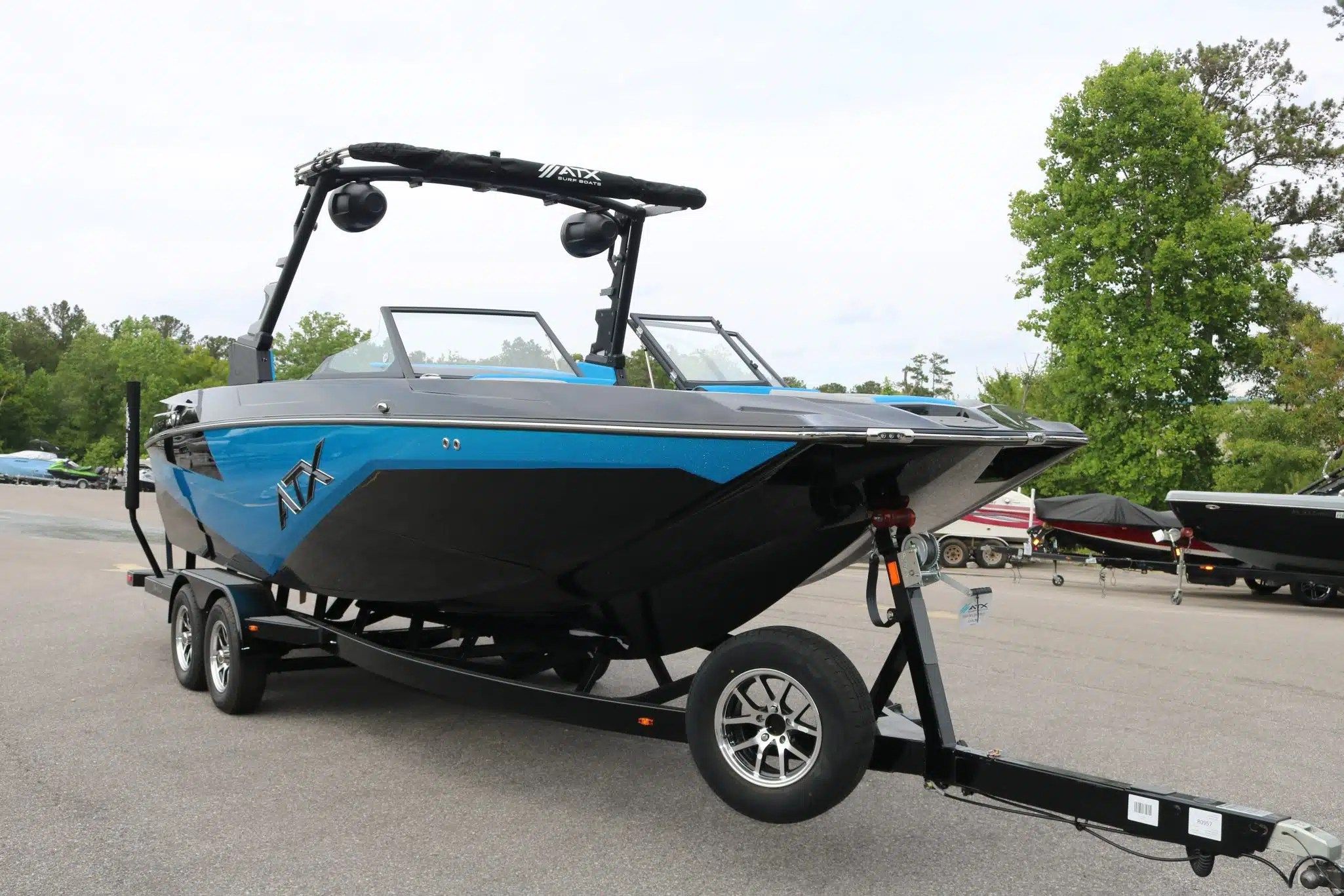 2024 ATX Surf Boats 24 Type-S on trailer, blue and black, in parking lot.