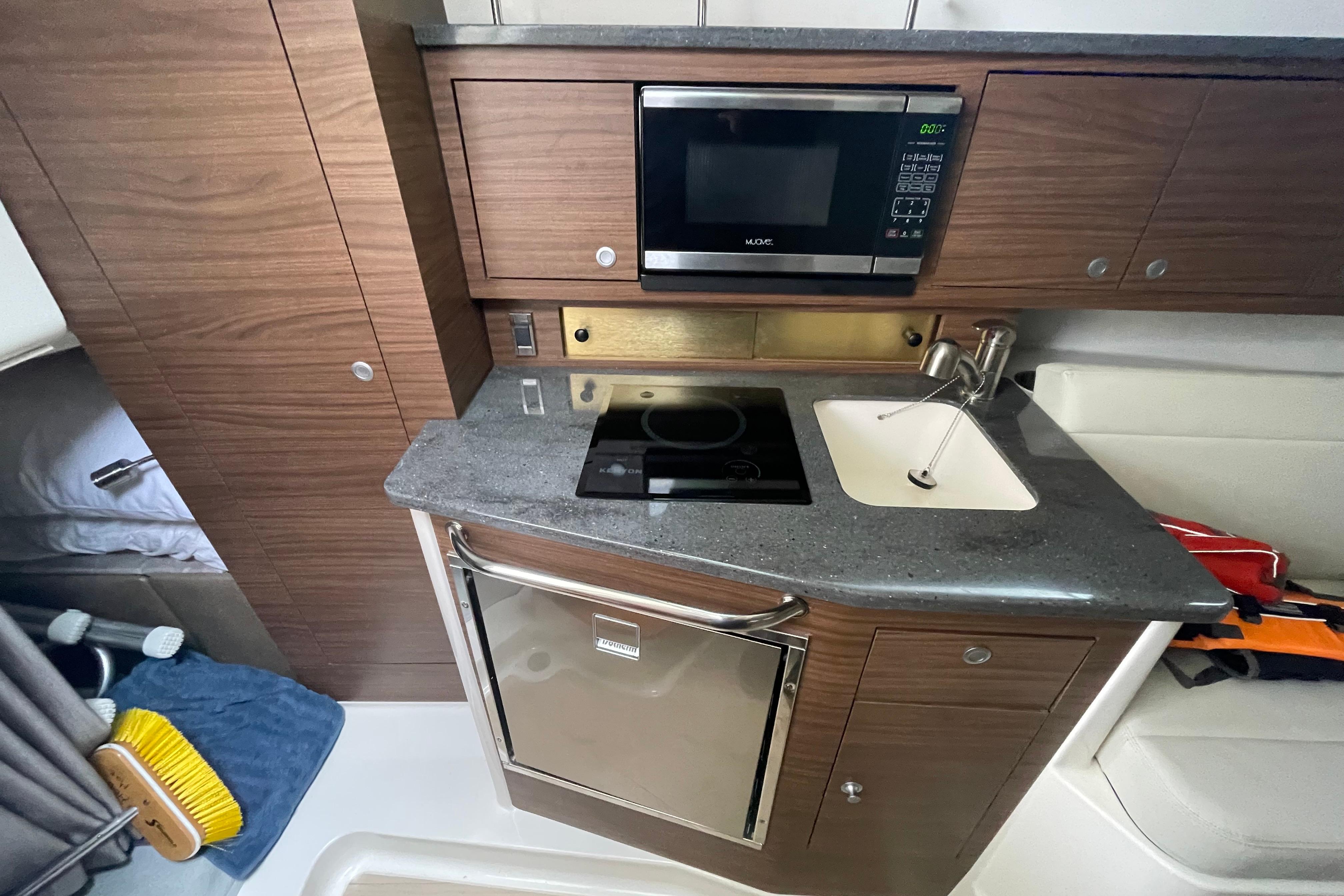 2023 Boston Whaler 325 Conquest galley with microwave, sink, and compact fridge.