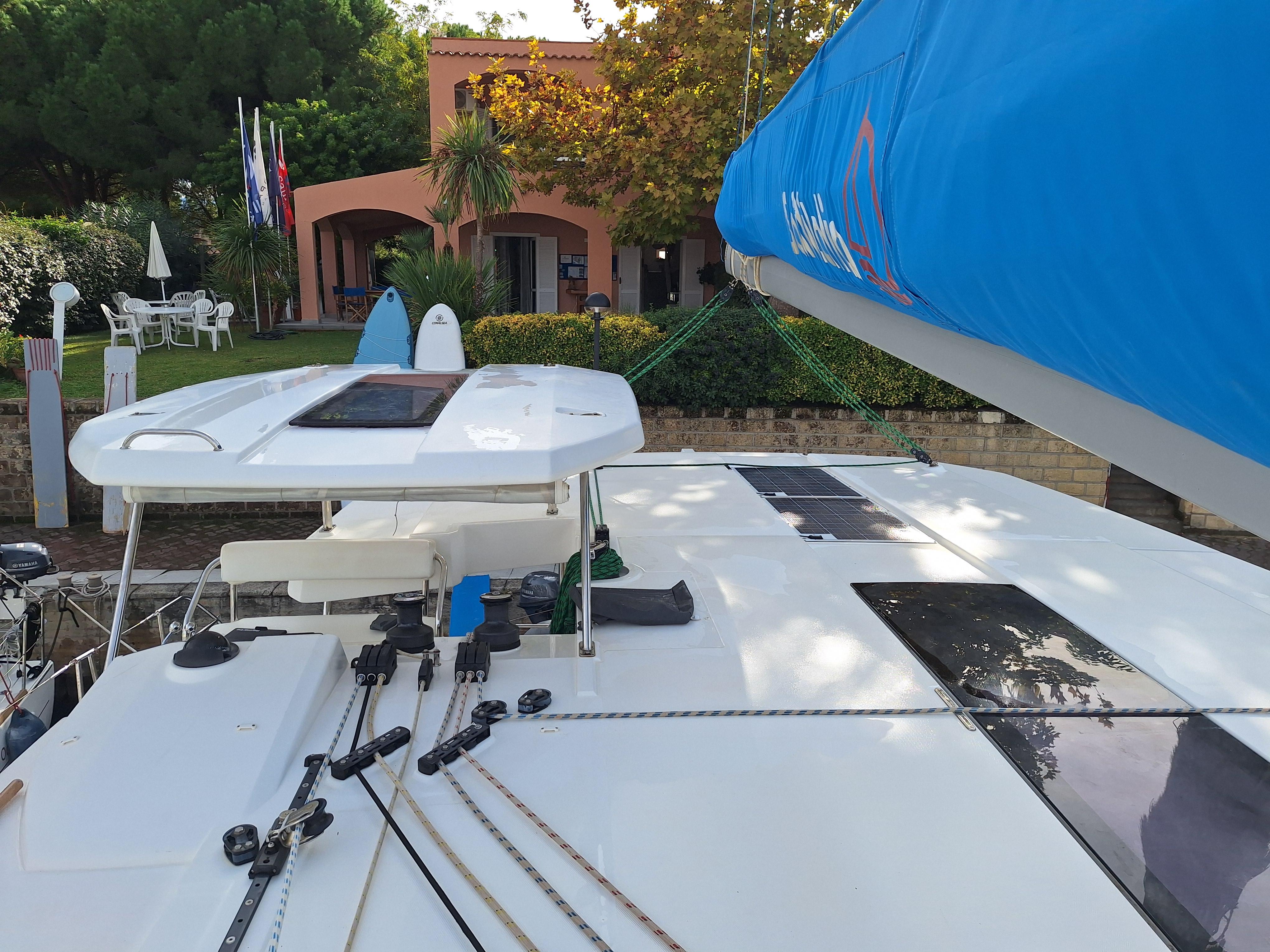 Leopard 45 catamaran docked near a garden, featuring a blue sail and modern design.