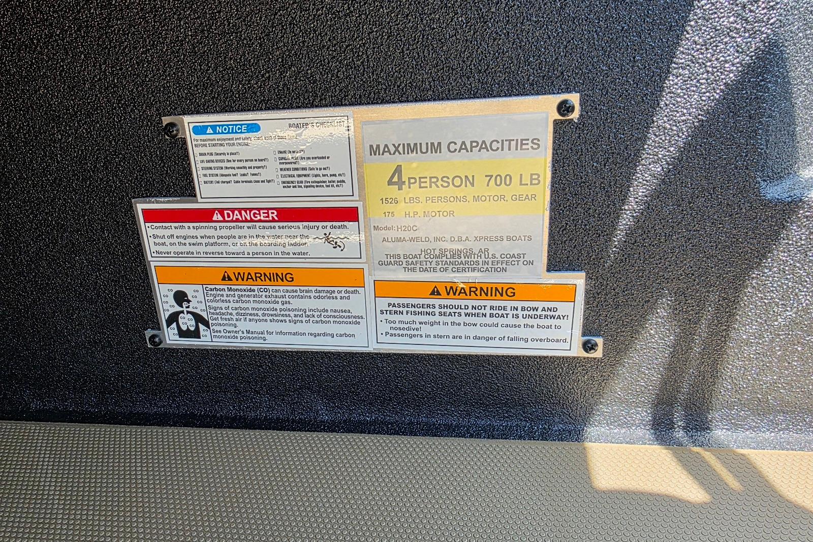 Safety and capacity labels on 2026 Xpress H20C Crappie boat, detailing weight and passenger limits.