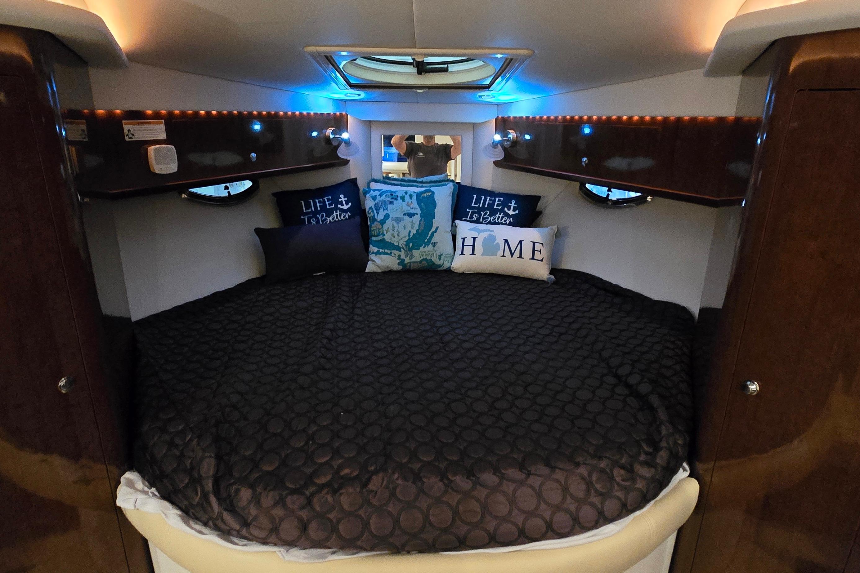 Cozy cabin interior of 2018 Four Winns V355 boat with decorative pillows and ambient lighting.