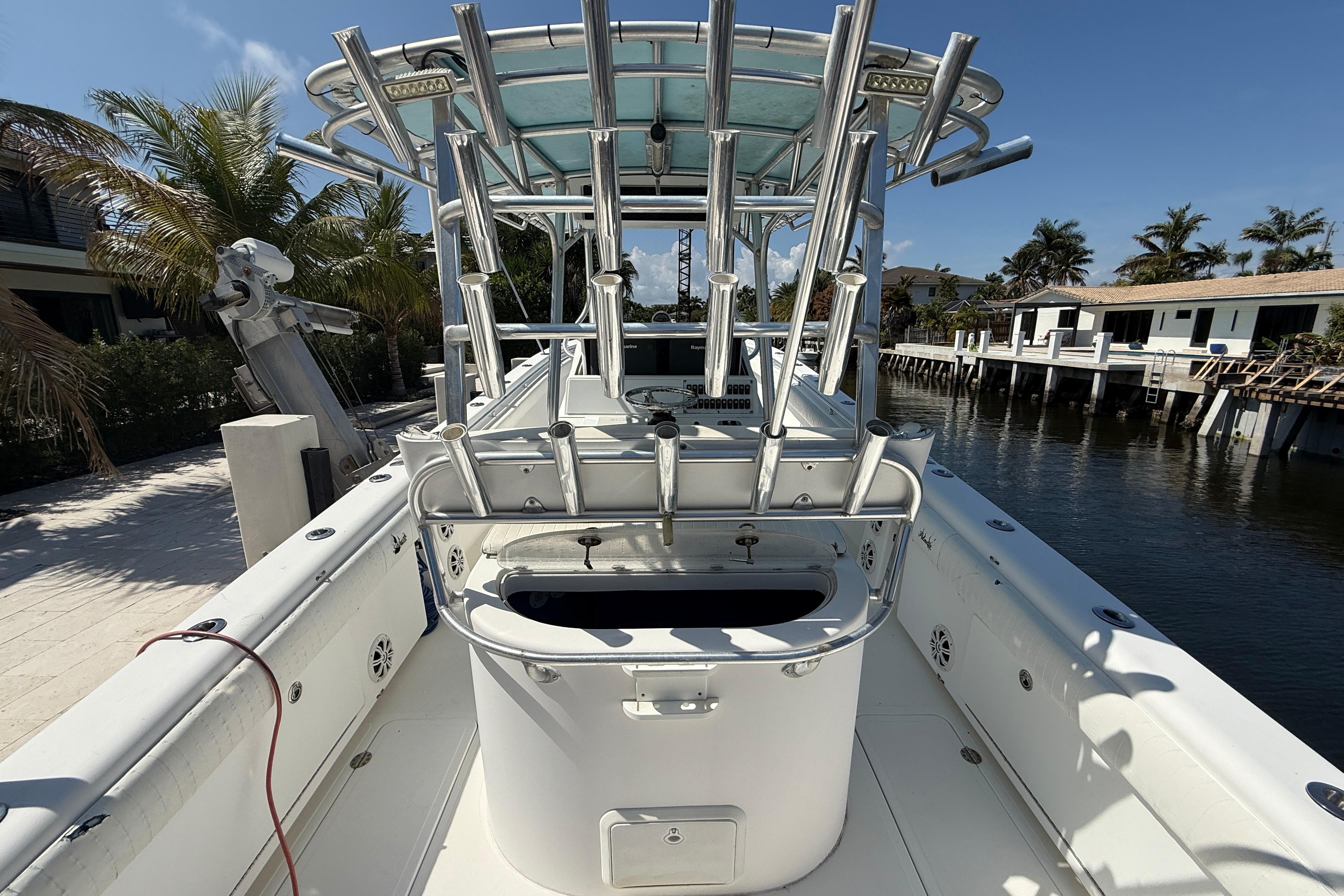 2003 Palmetto 33 Adventure boat docked by waterfront homes, featuring rod holders and a spacious deck.