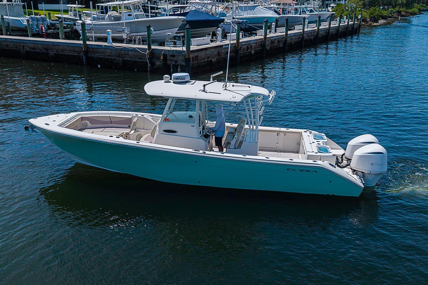 2019 Cobia 320 Center Console boat cruising in marina waters.