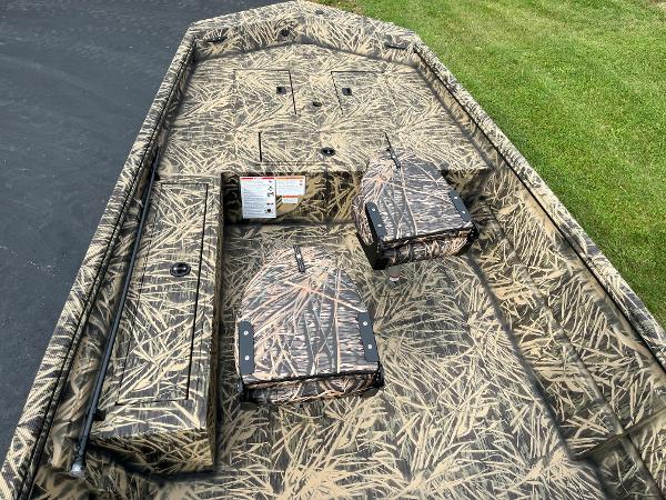 2024 Lowe Roughneck 1660 boat interior with camouflage design, featuring storage compartments and seating.