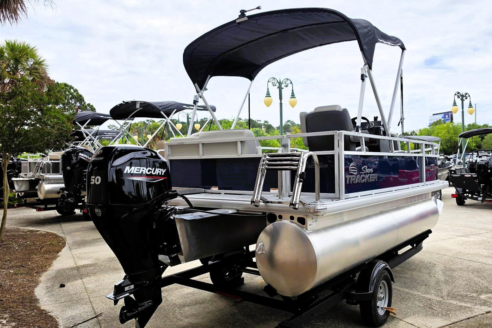 2026 Sun Tracker Bass Buggy 16 XL Select pontoon boat with Mercury engine, parked outdoors.