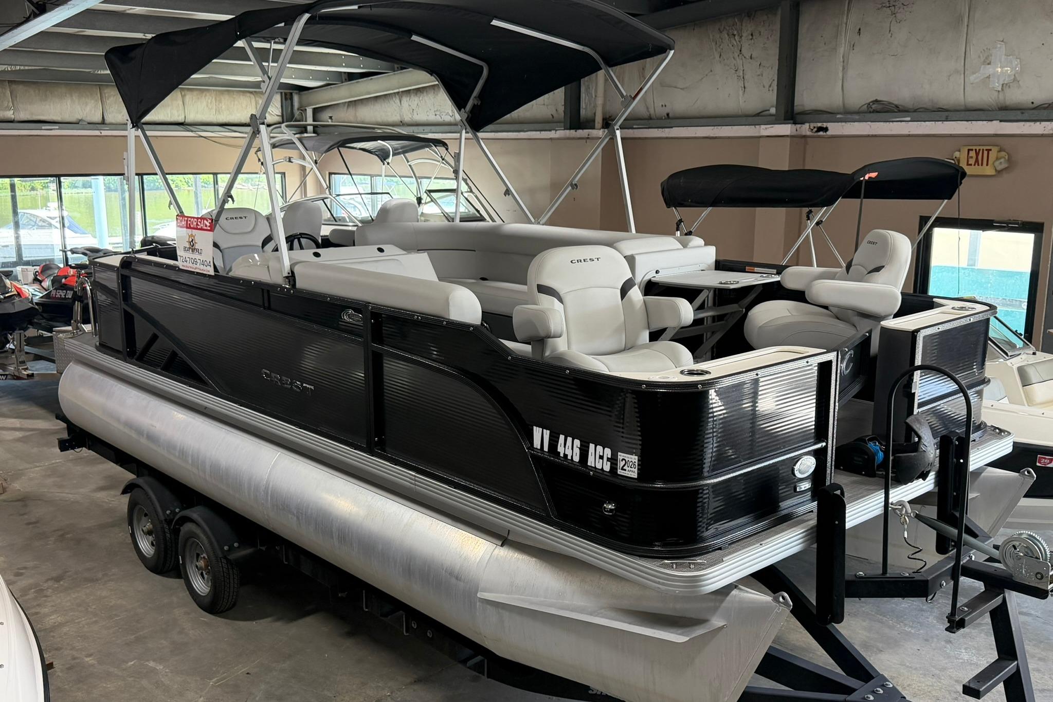 2023 Crest Classic LX 200 pontoon boat with canopy, displayed indoors on a trailer.