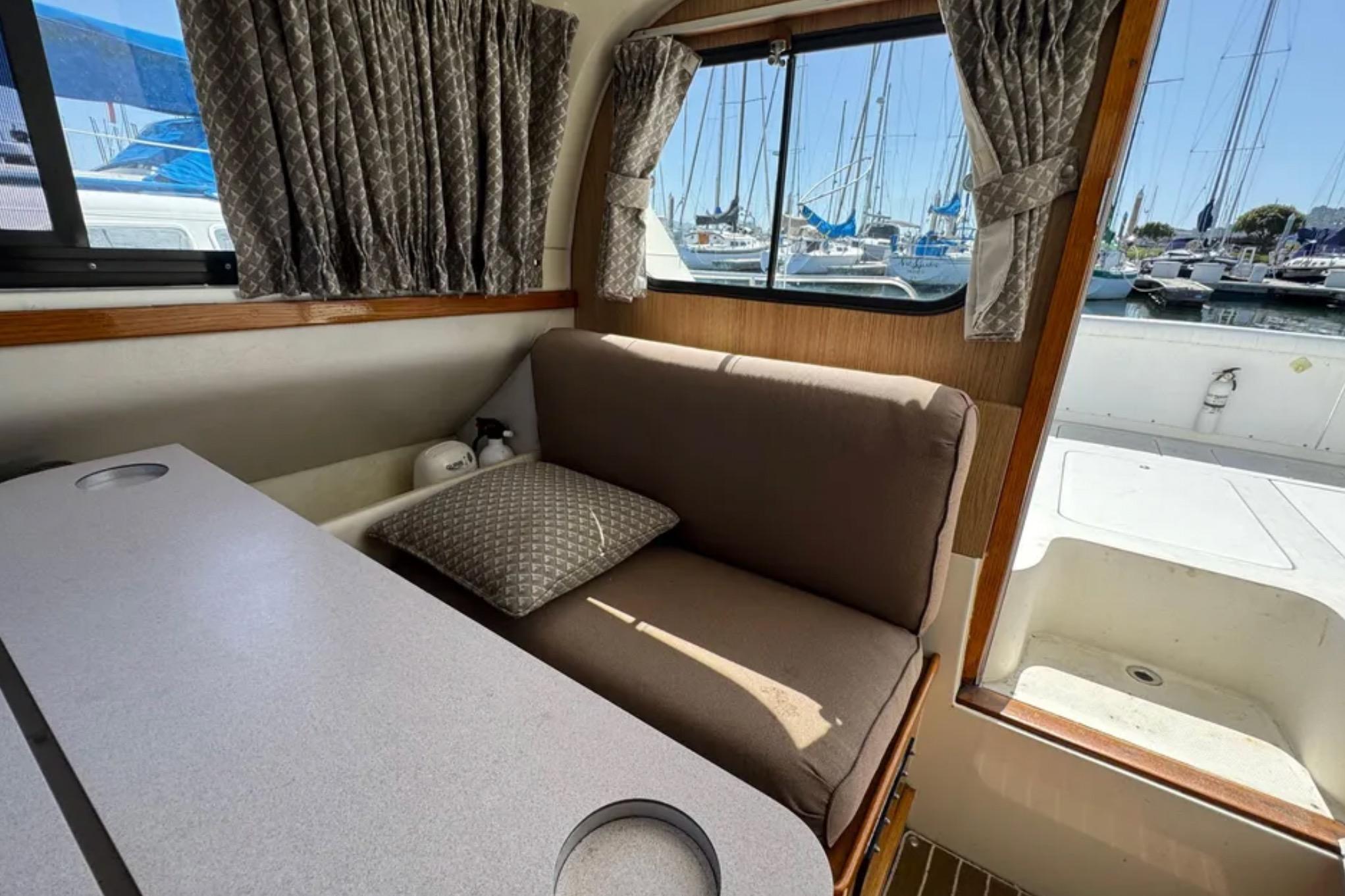 Interior of 1988 Bertram 28 Sport Fisherman with seating, table, and marina view.