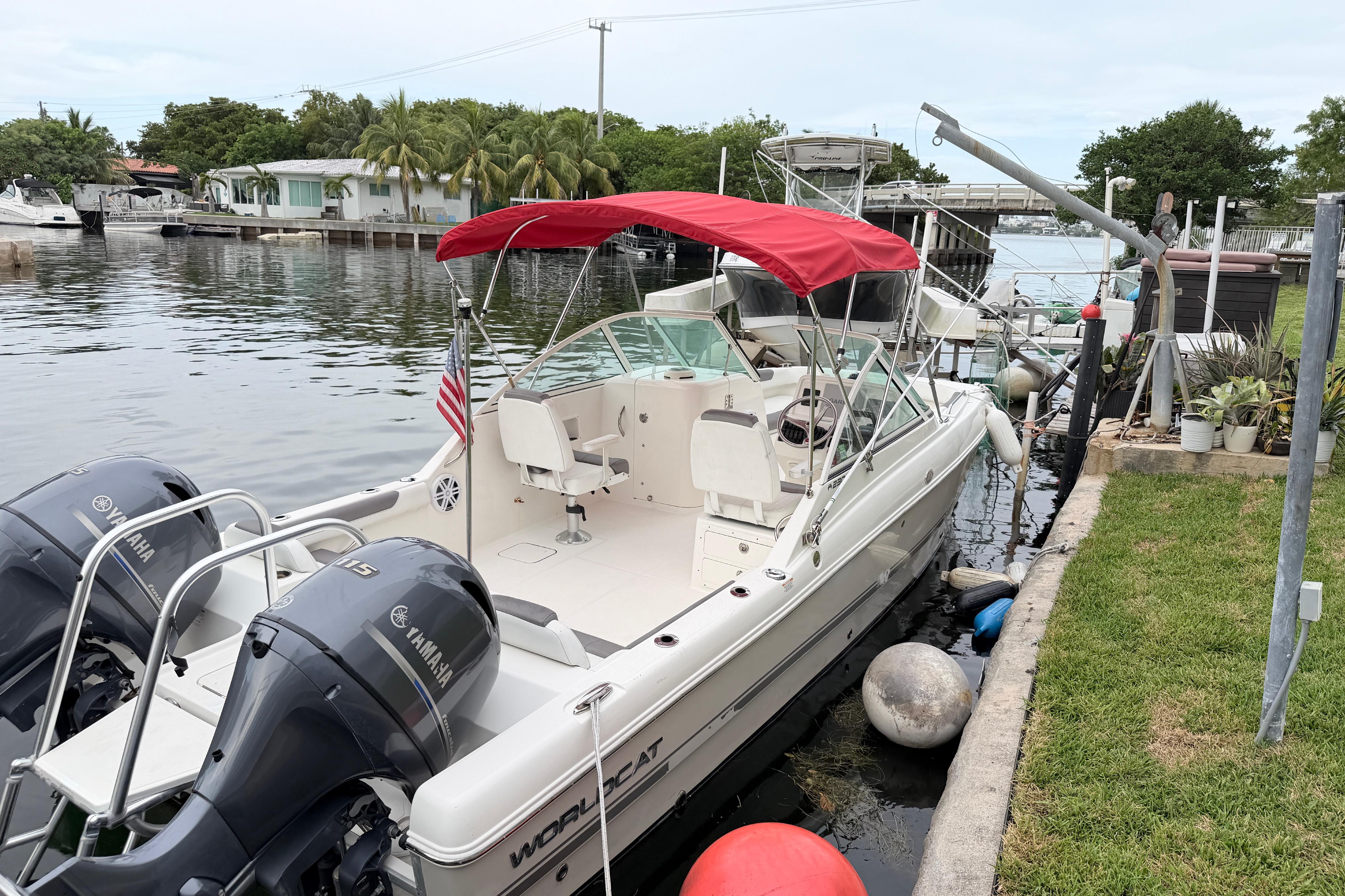 2019 World Cat 230 DC boat docked with red canopy and twin Yamaha engines.