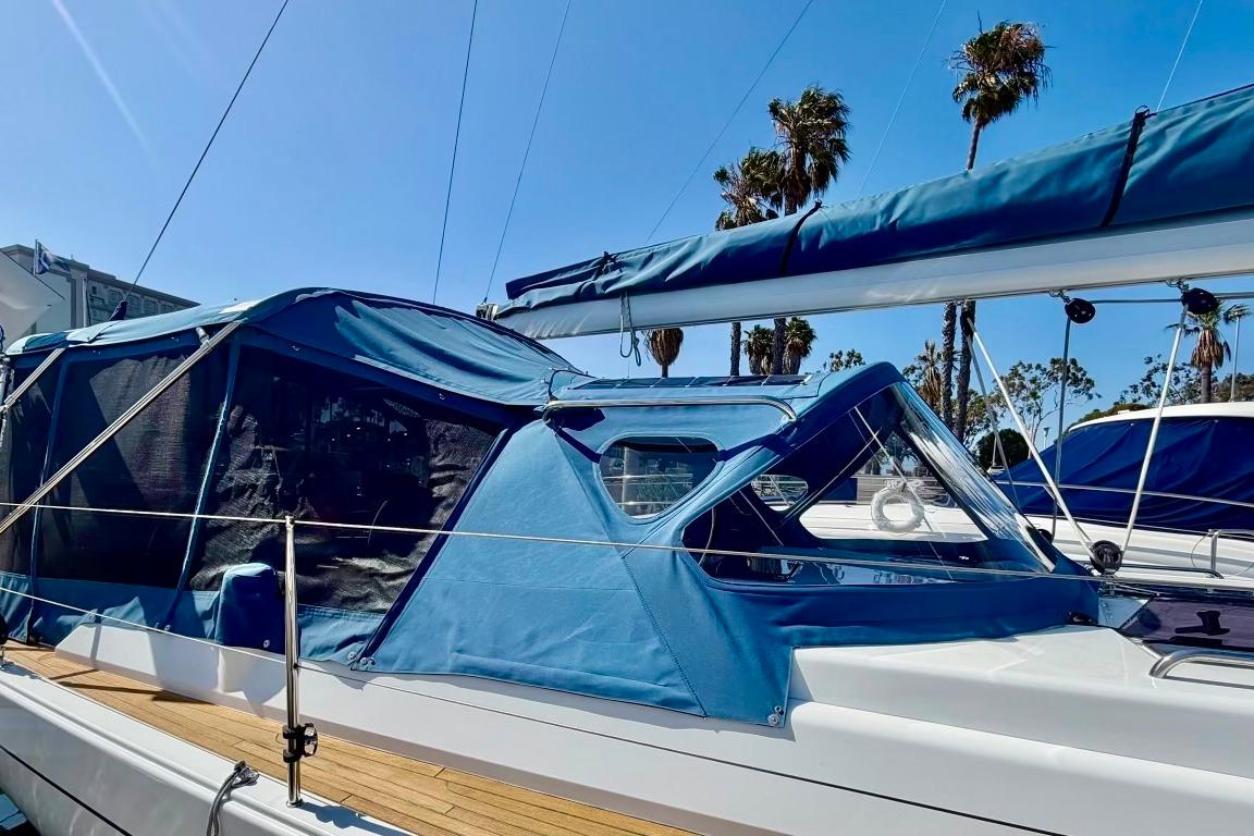 2016 Hanse 455 sailboat with blue canopy, docked under clear skies and palm trees.