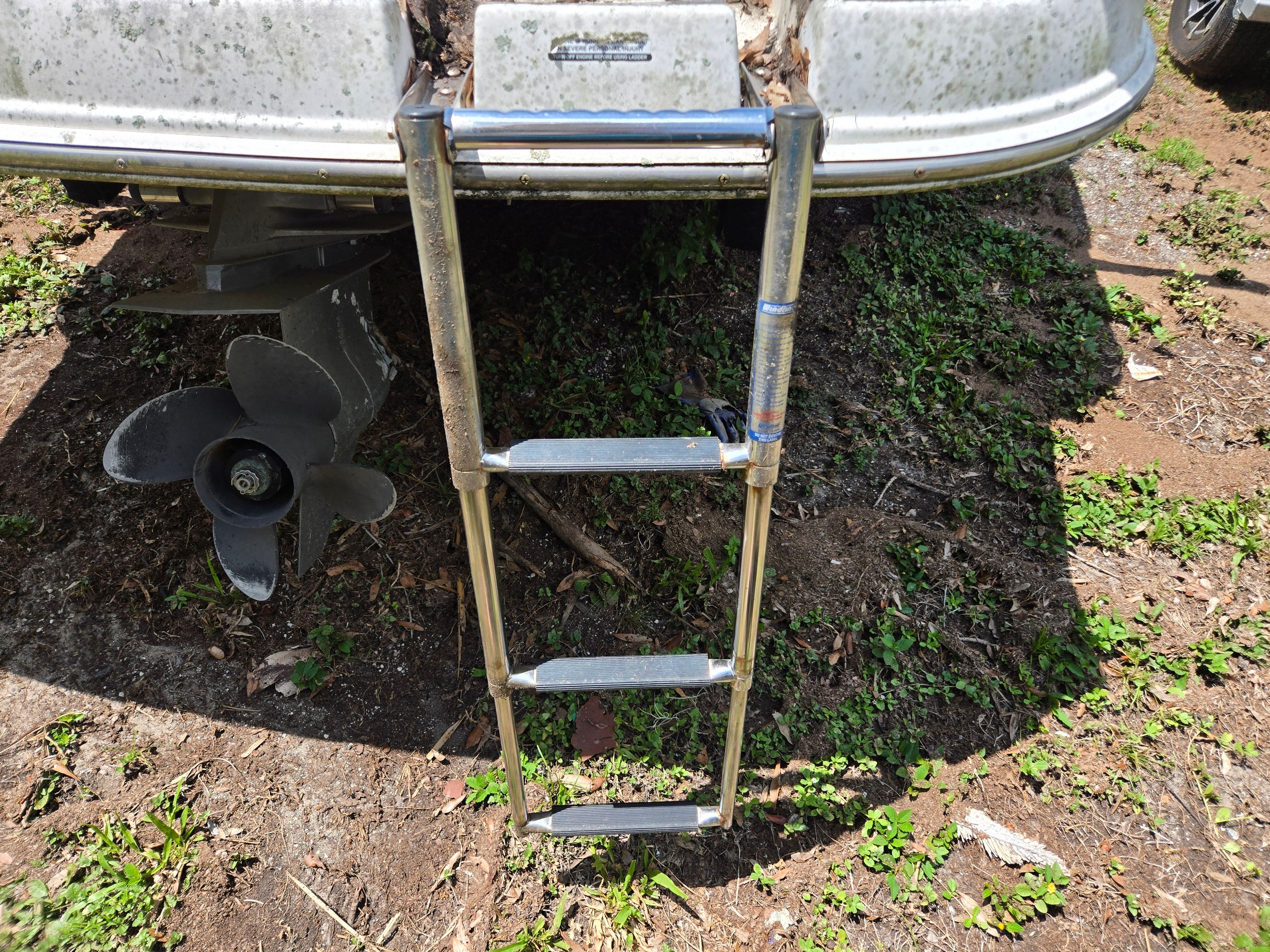 A swim ladder at the back of a boat, with a propeller underneath.