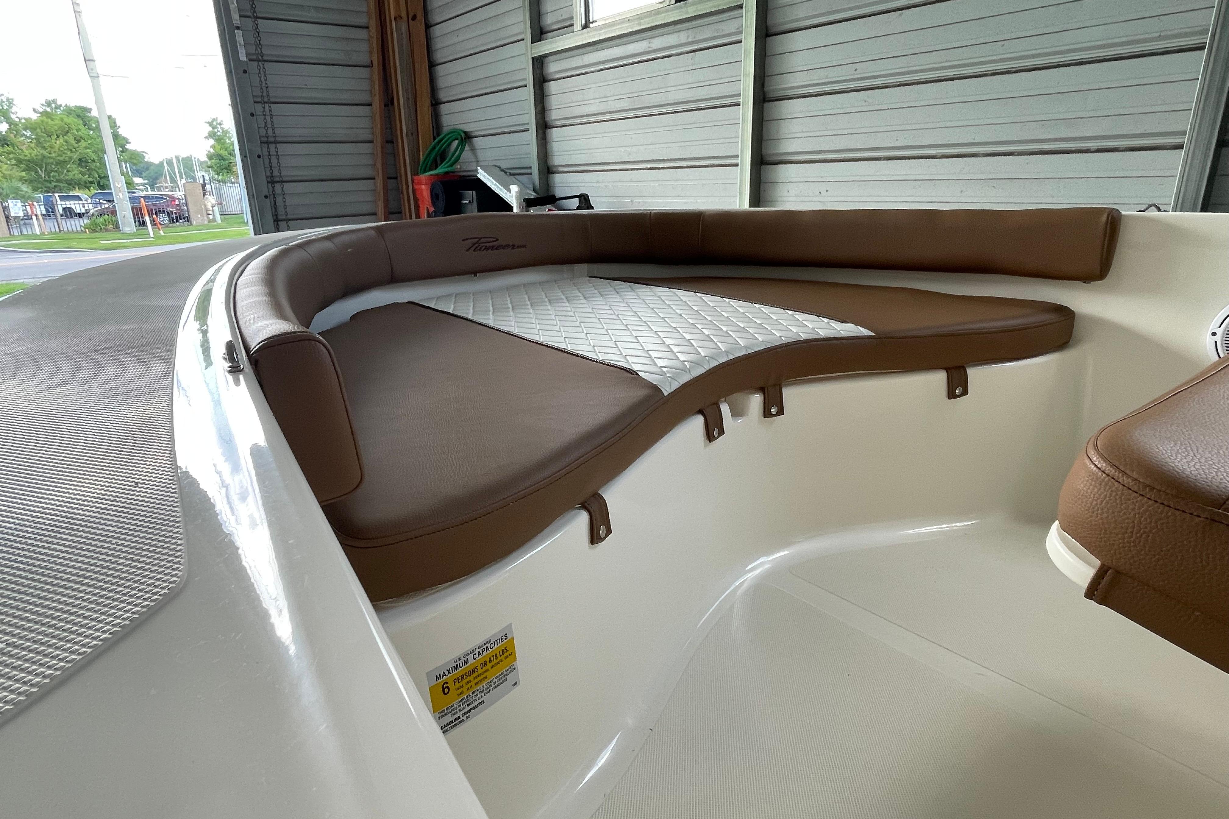 2024 Pioneer 180 Islander boat interior with brown cushioned seating in a garage.