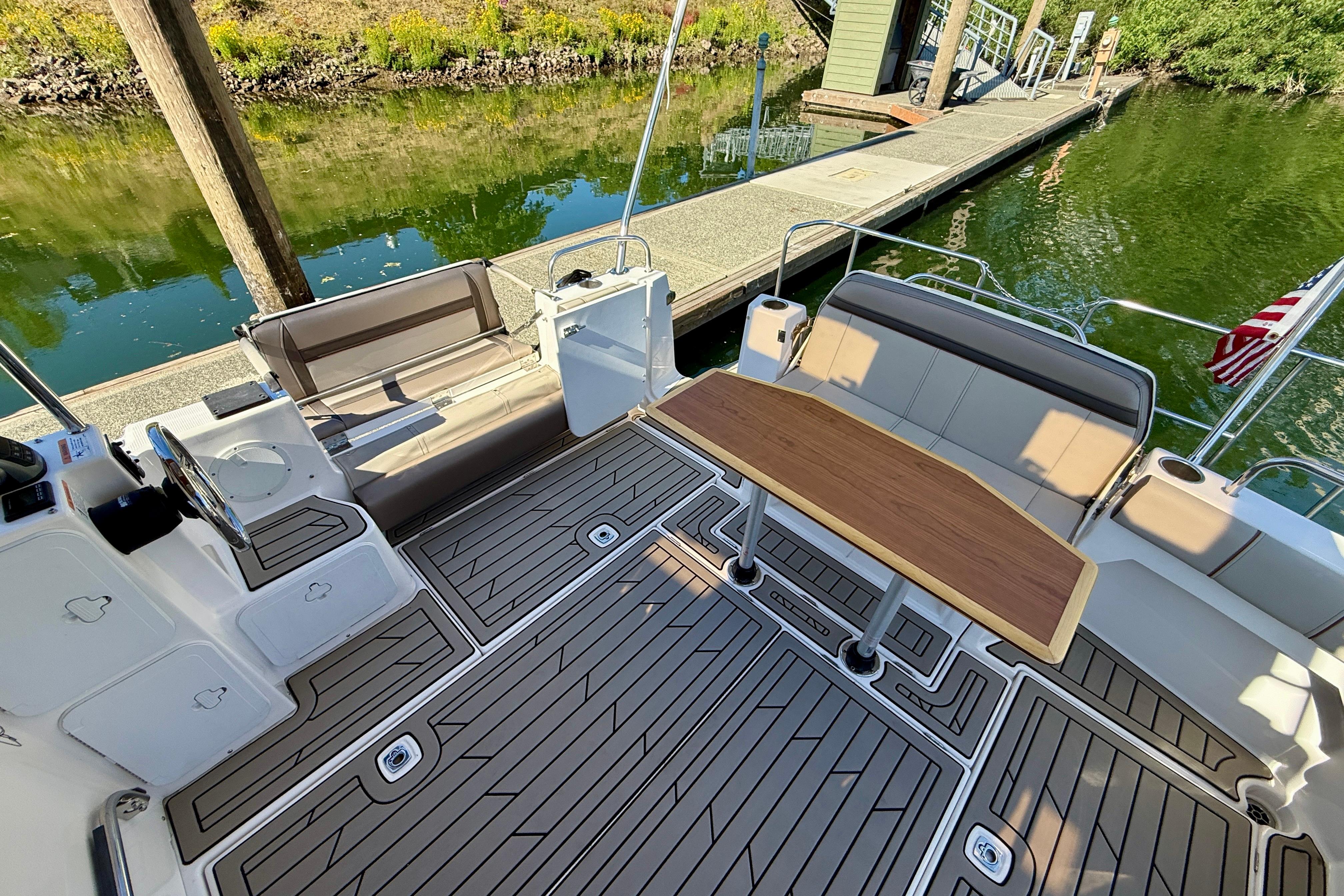 2023 Cutwater C-30 Sedan boat interior with seating and table, docked by a calm waterway.
