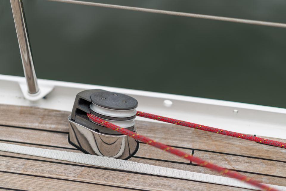 Pulley system on 1991 Devonport Thomas Custom 67 yacht deck with red rope.