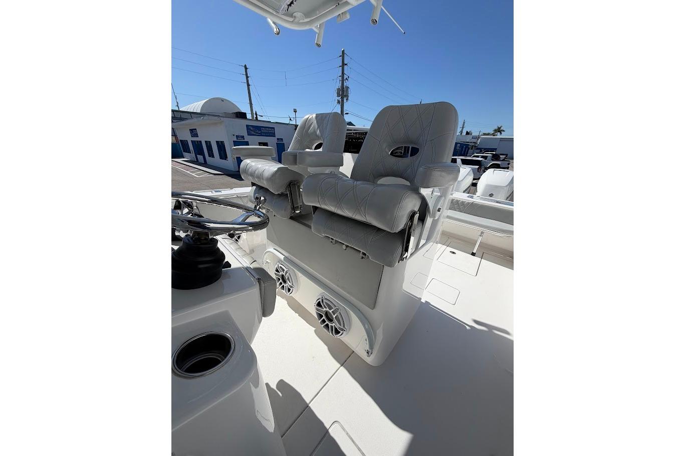 2021 Contender boat with dual cushioned seats and steering wheel, docked under clear blue sky.