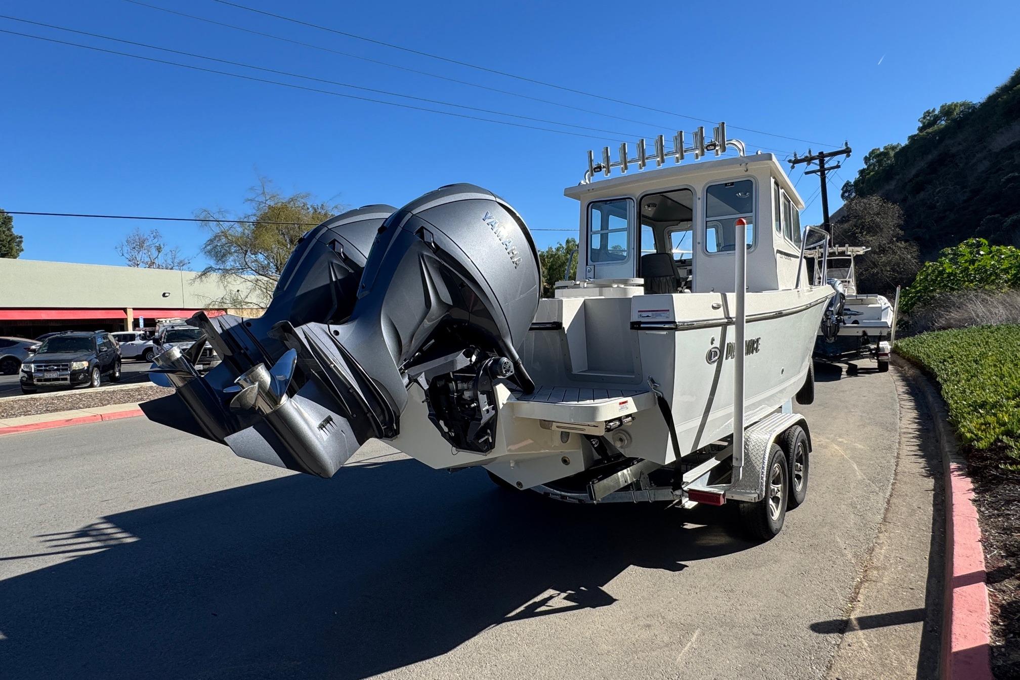 2026 Defiance Admiral 250 EX boat on trailer, dual outboard motors, parked on roadside.